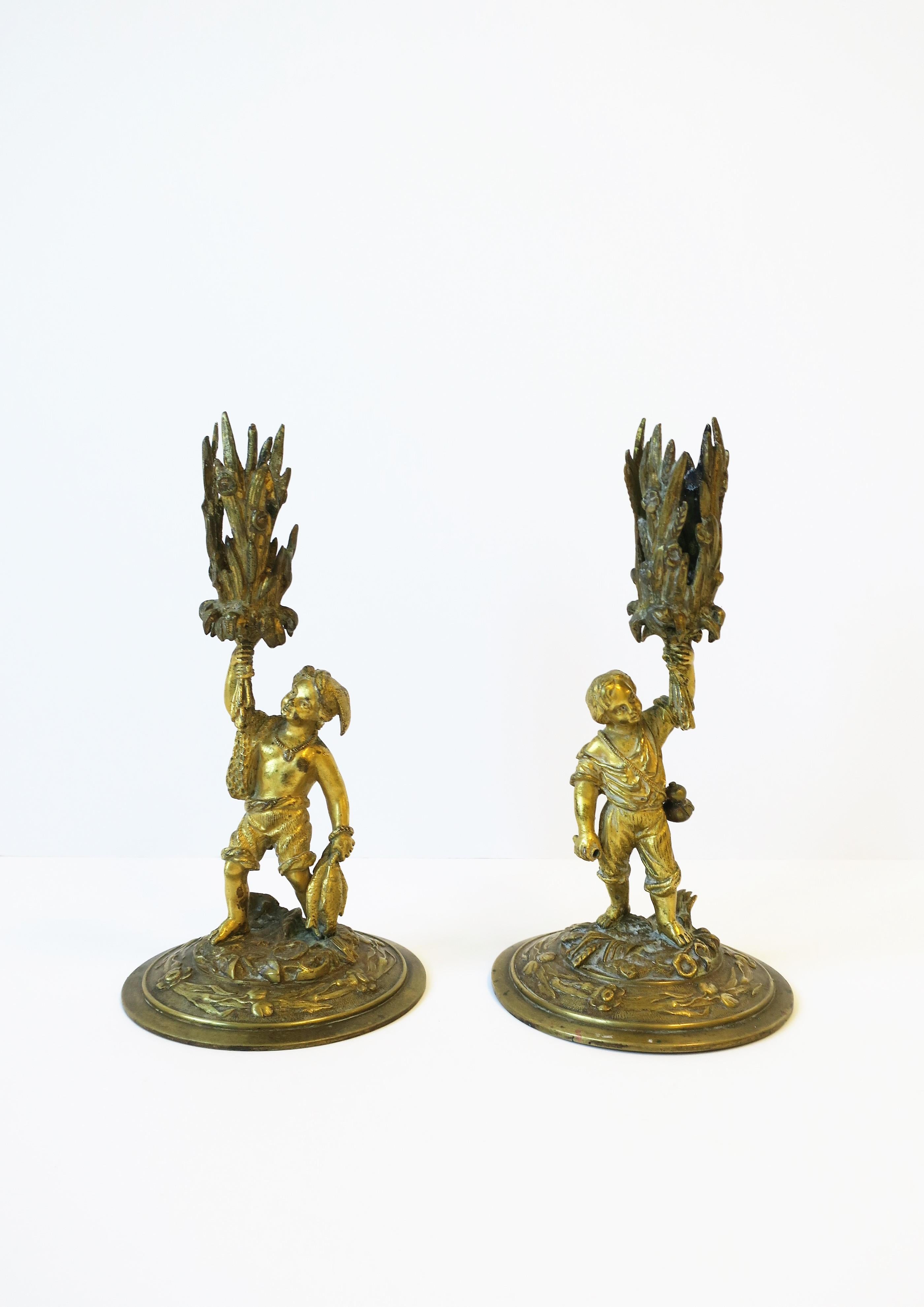 A pair of gilt bronze young male figurative sculptures candlestick holders, circa 19th Century, Europe. A beautiful pair with many details including each holding a bunch of sheaf-of-wheat. And it appears the pair had gone fishing; fishing net over