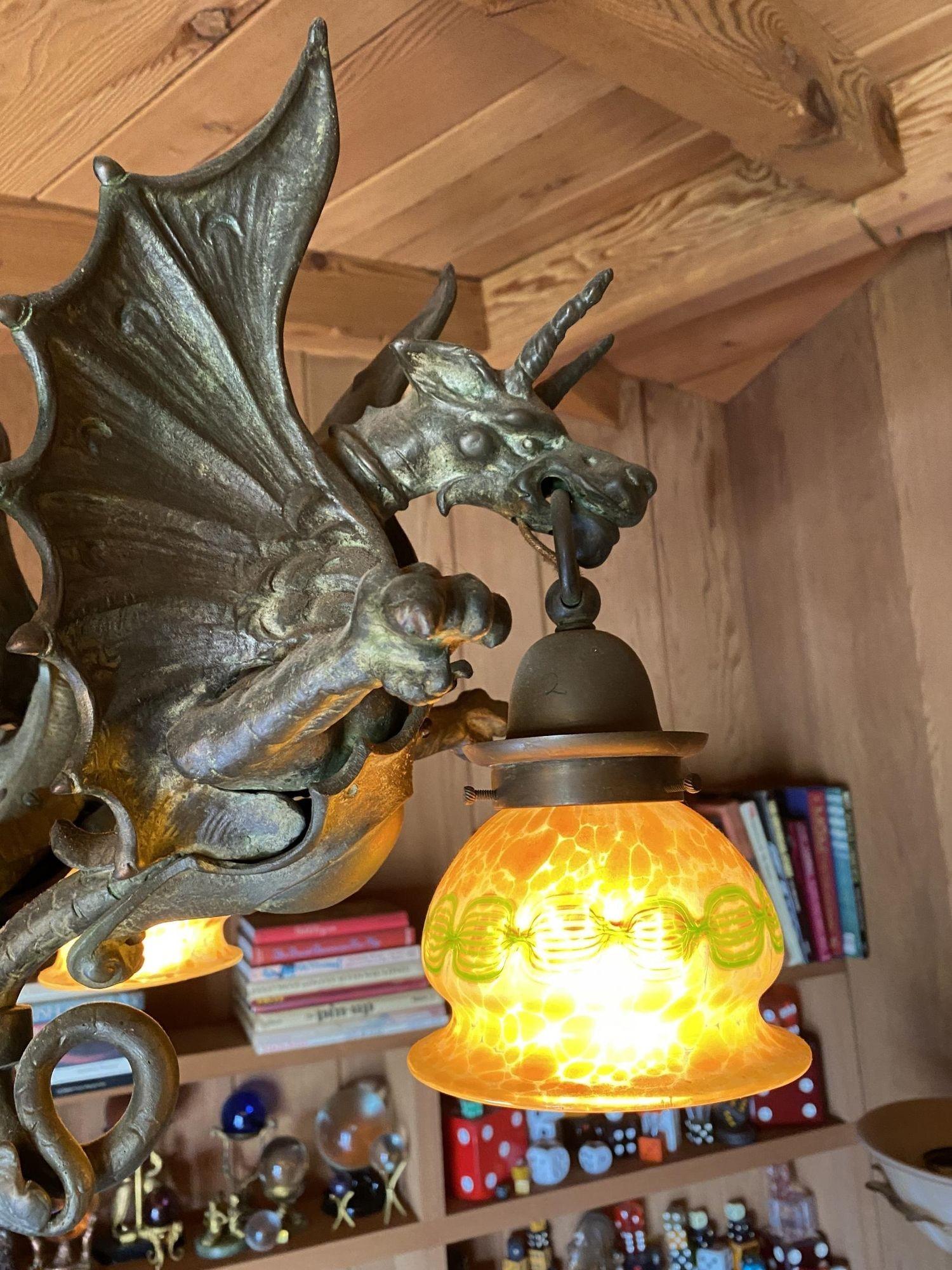 A custom chandelier with lost wax bronze cast dragons and Spanish alabaster shades, this chandelier also consists of a solid bronze ball with hook style canopy and solid bronze chain.

The lantern-style dragon shades are American quezal gold