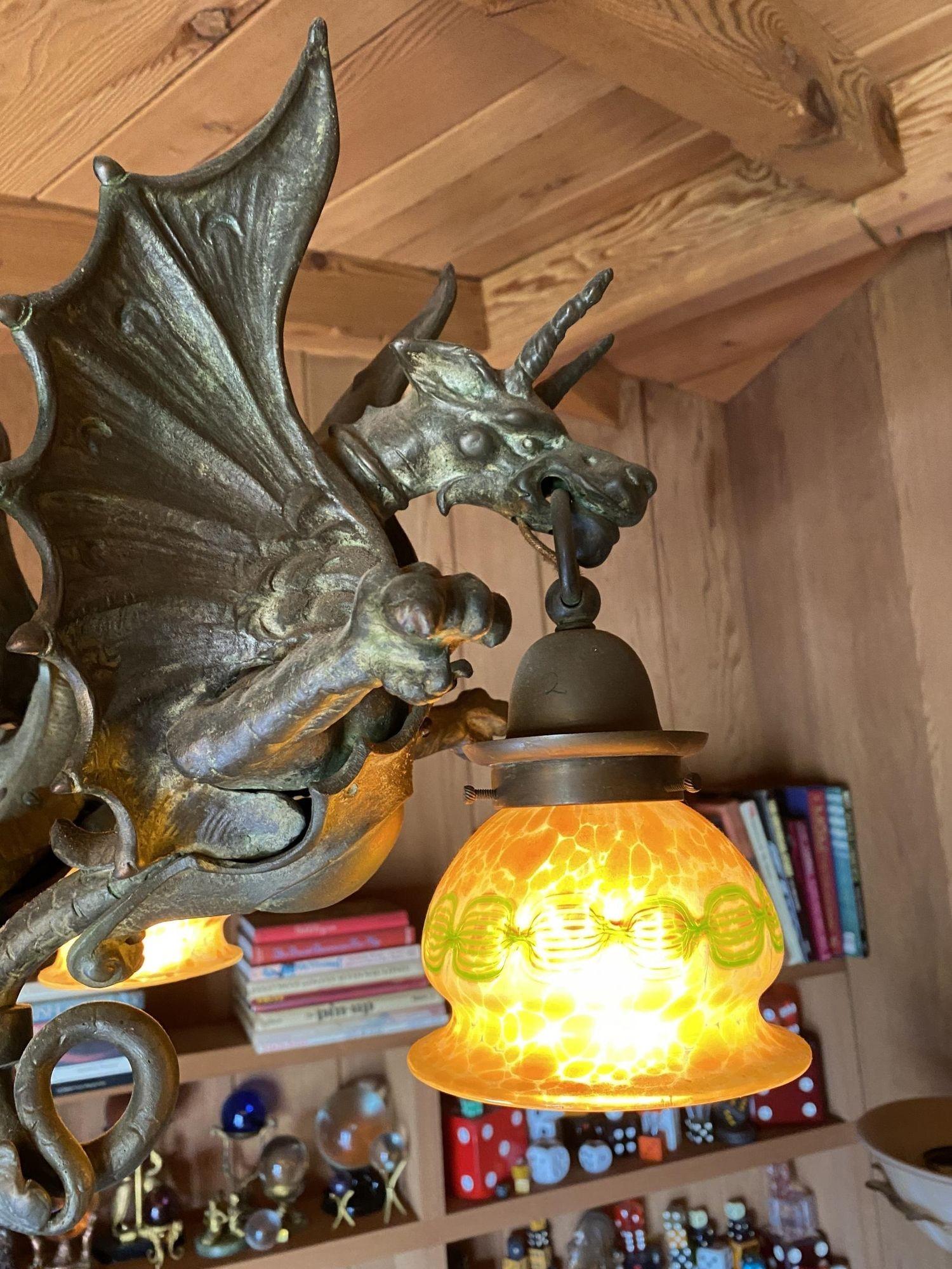 A custom chandelier with lost wax bronze cast dragons and Spanish alabaster shades, this chandelier also consists of a solid bronze ball with hook style canopy and solid bronze chain. The lantern-style dragon shades are American quezal gold