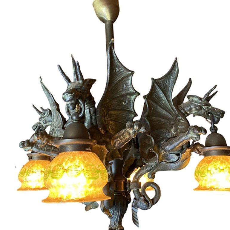Dieser maßgefertigte Kronleuchter besteht aus in Wachsausschmelzbronze gegossenen Drachen. Die laternenartigen Drachenschirme sind aus mundgeblasenem, goldschillerndem amerikanischem Quezal-Glas. Die Bronzeteile des Kronleuchters sind mit einer