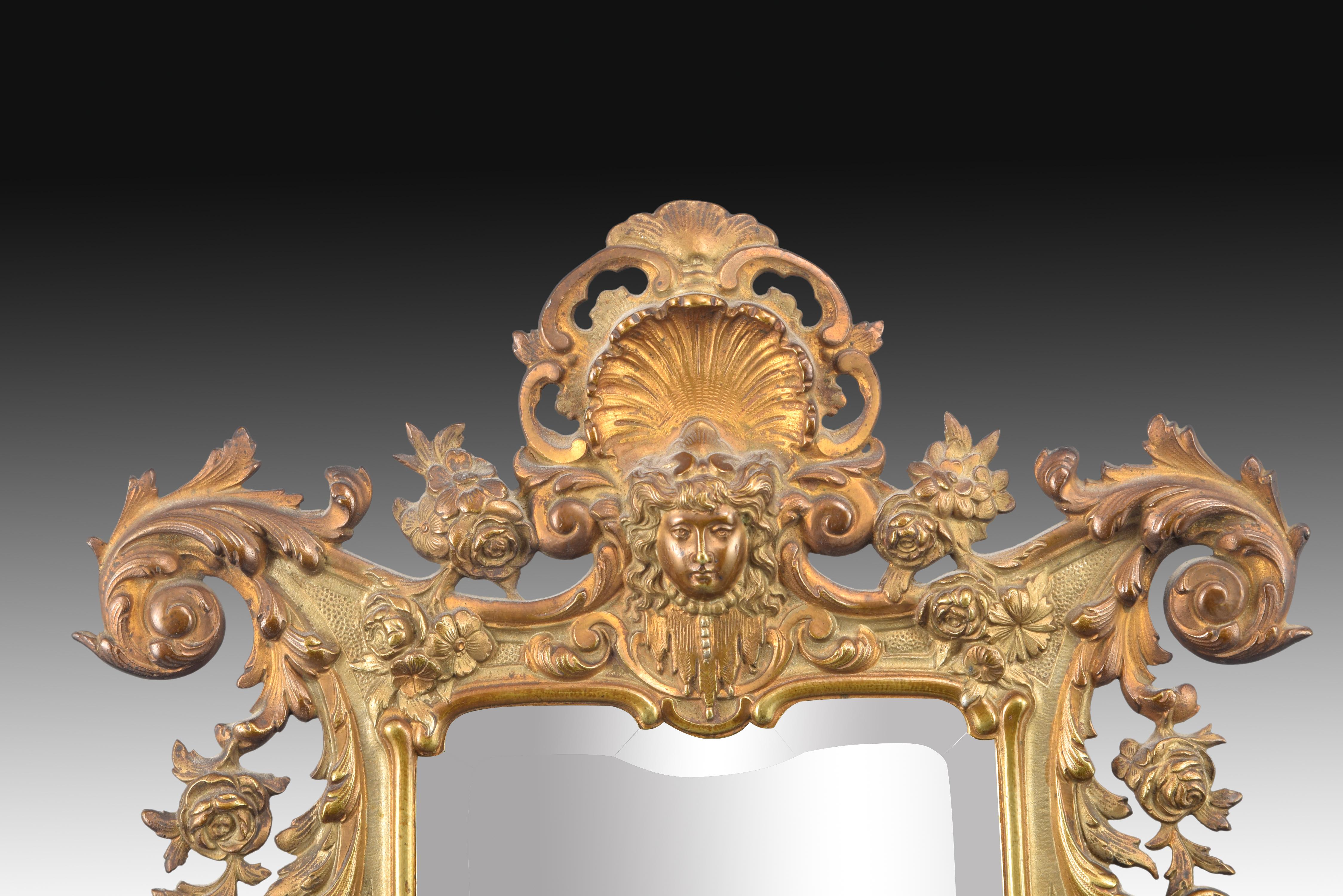 Mirror. Bronze, 19th century.
Rectangular mirror with the frame made of bronze and decorated with an elaborate composition, partially openwork, arranged symmetrically in the two lateral halves based on plant elements, architectural motifs, scrolls,