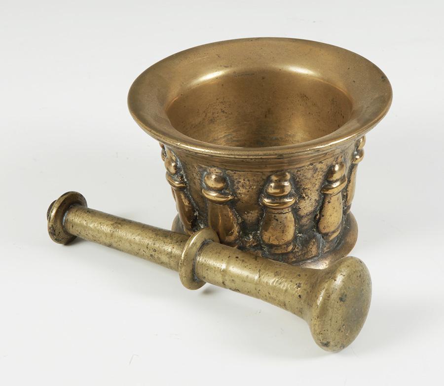 Mortar in bronze of baroque epoch, with structure in the form of inverted bell with circular flat base and exvasada mouth. It is decorated with embossed columns in relief, obtained to mold, ten in total, which fulfil the function of the usual ribs