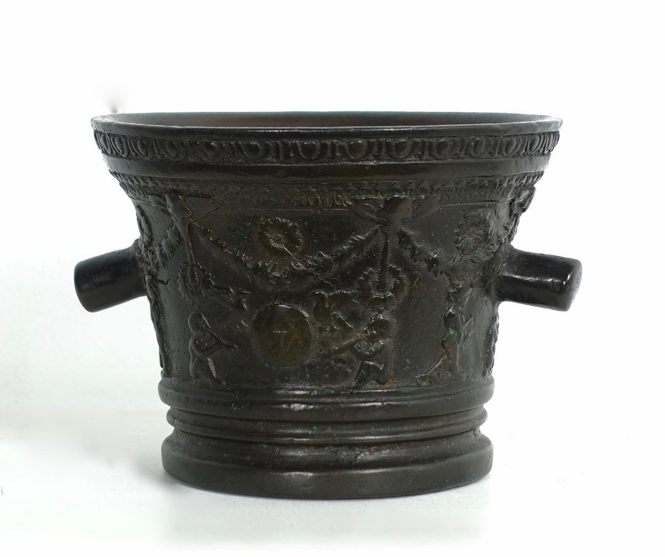 Mortier en bronze avec guirlandes, fleurs et putti - Toscane, seconde moitié du XVIIe siècle.
Dimensions : hauteur 10 
diamètre : 13 cm

Les artisans et les guérisseurs utilisaient des mortiers pour broyer les aliments, les teintures et les
