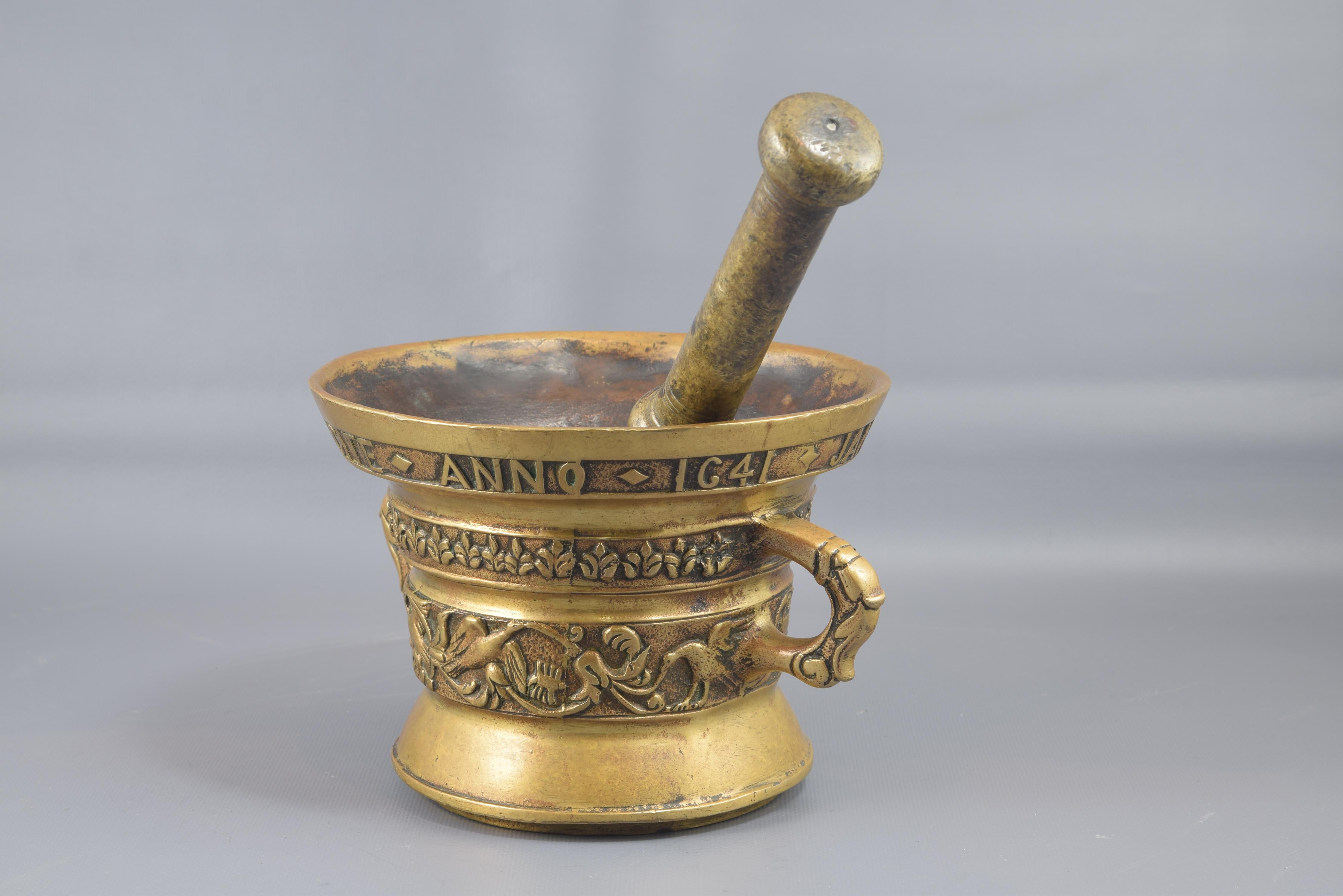 Mortar with hand. Bronze, 20th century.
Open-ended cylindrical mortar with two handles, a decoration in bands on the outside (rolls and birds; floral details; inscription in capital letters 