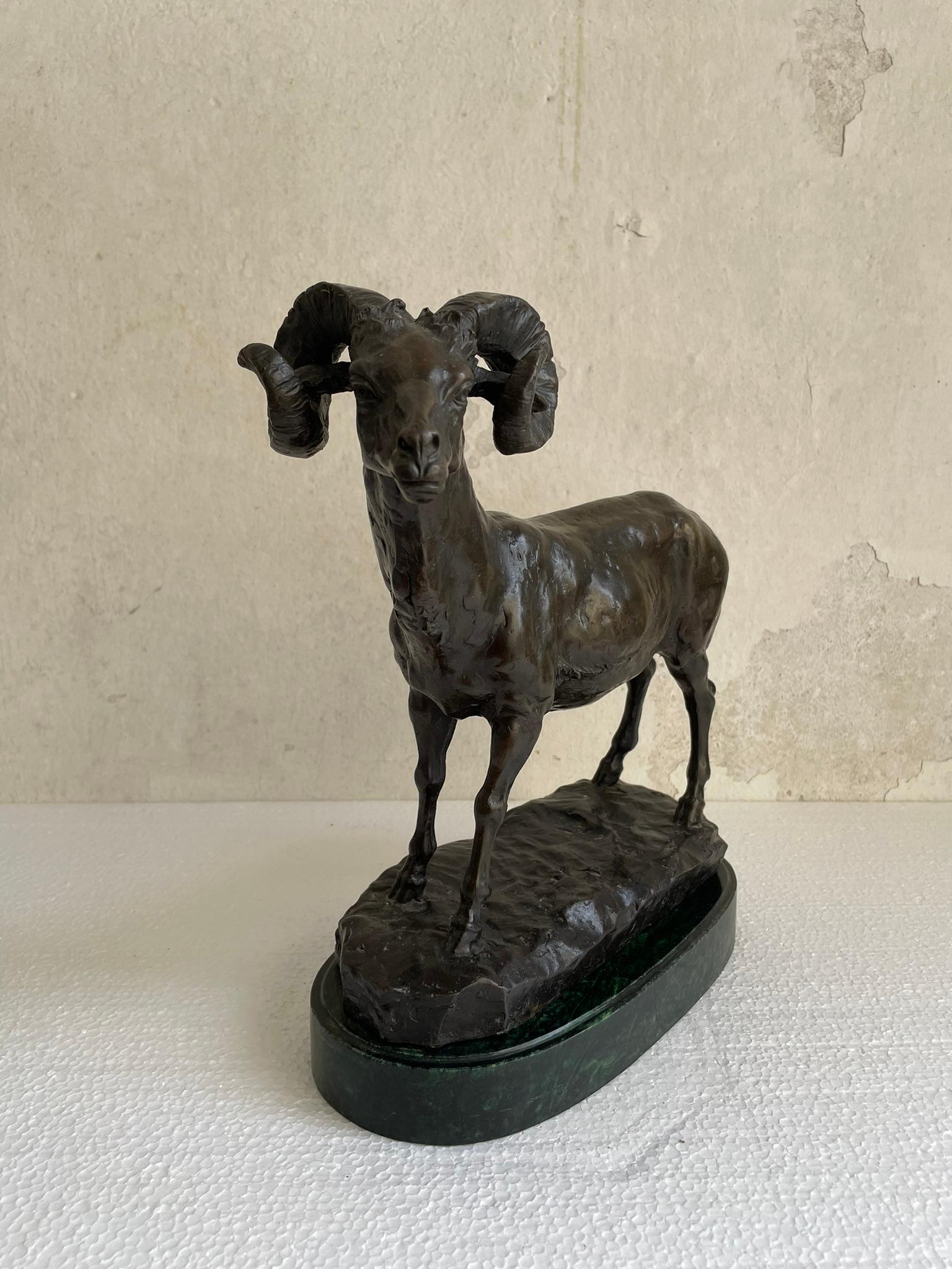 La statua è realizzata in bronzo, con una finitura scura e lucida. Il muflone è raffigurato in posizione eretta, con tutte e quattro le zampe posizionate su una base che ricorda una superficie rocciosa. La base è ovale e di colore verde scuro,