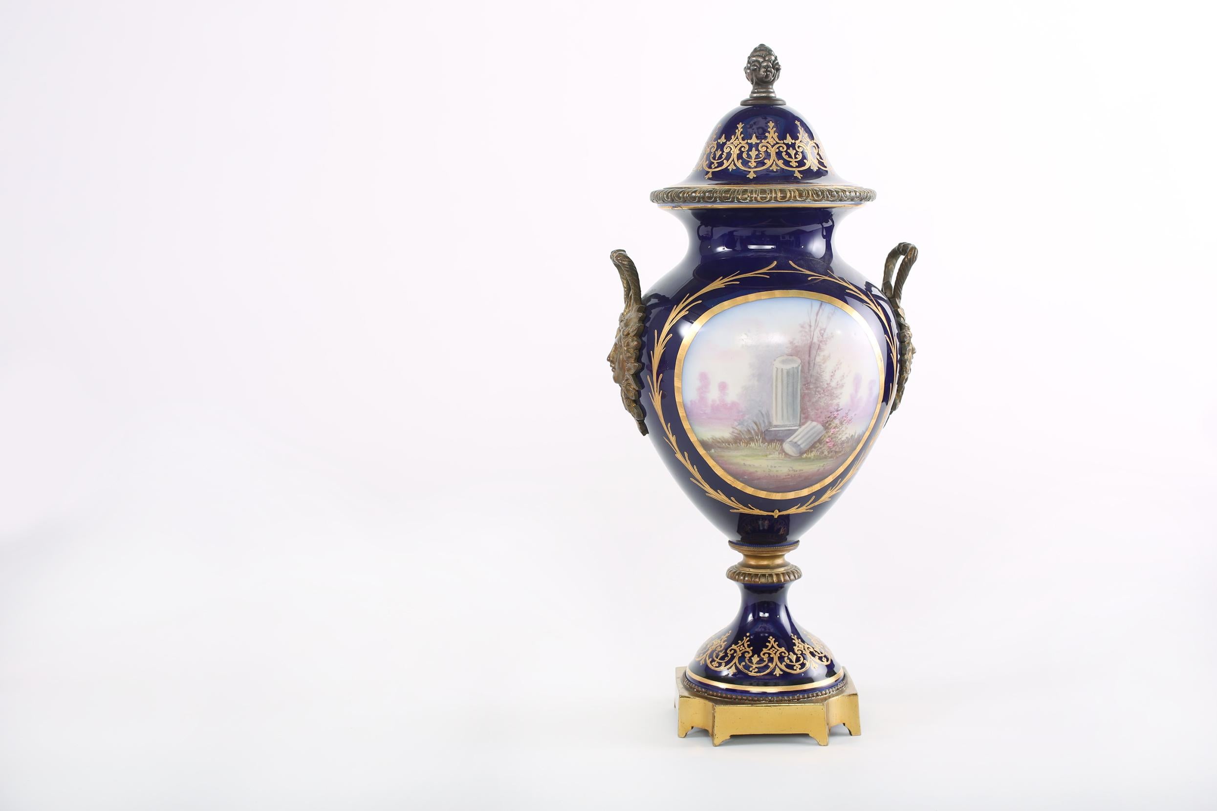 Bronze mounted / Sèvres Porcelain covered decorative urn with side handles & exterior painted scene design details. The urn is in good antique condition. Minor wear appropriate with age / use. Covered with repaired hair line. The urn stand about 18