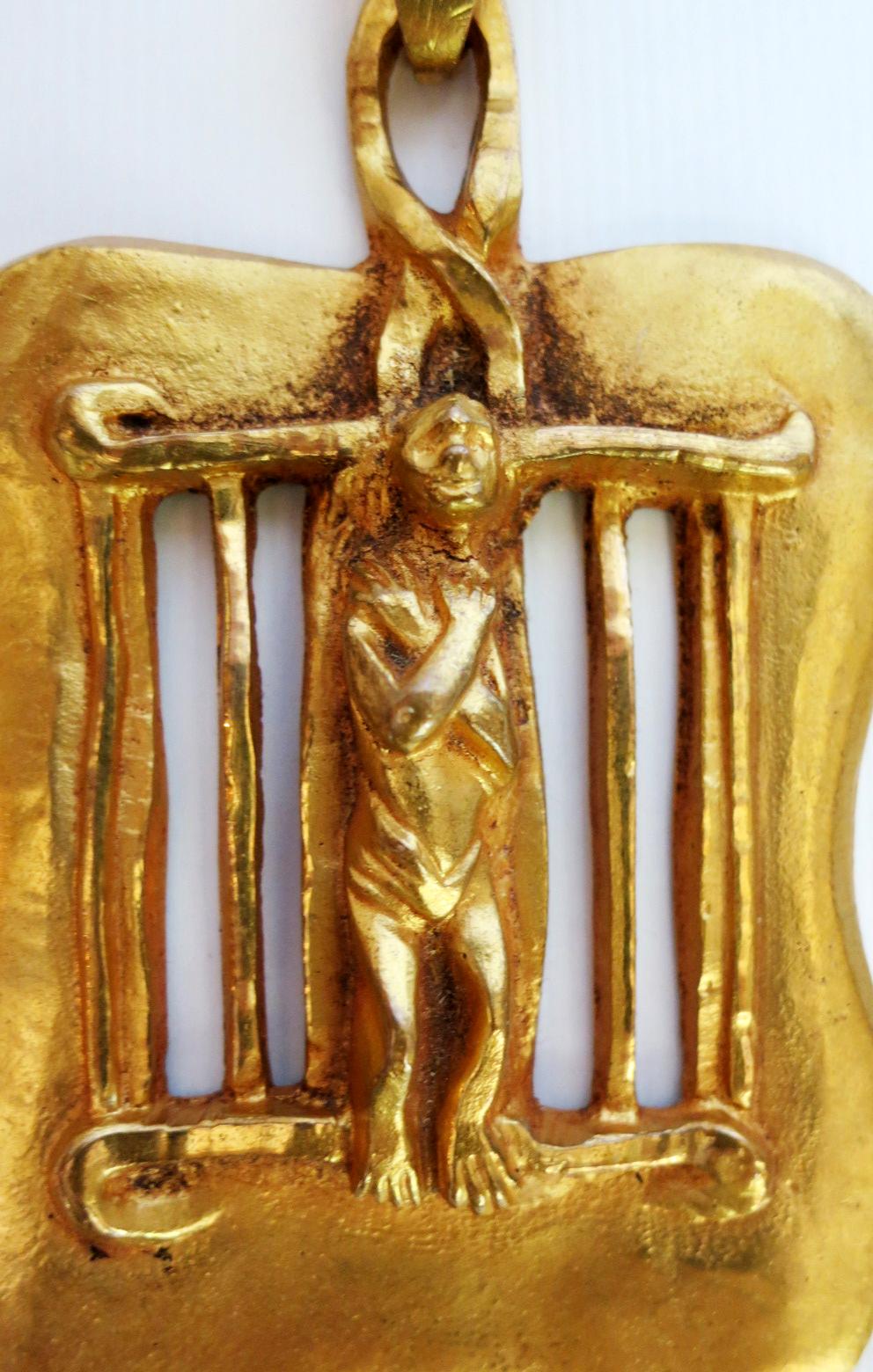 A cast bronze pendant titled Saint Laurent by French art jewelry designer Line Vautrin (1913-1997). Gilt bronze, circa late 1940s. It depicts the 3rd century Christian Saint Lawrence (known as St. Laurent in France) was martyred being slowly roasted