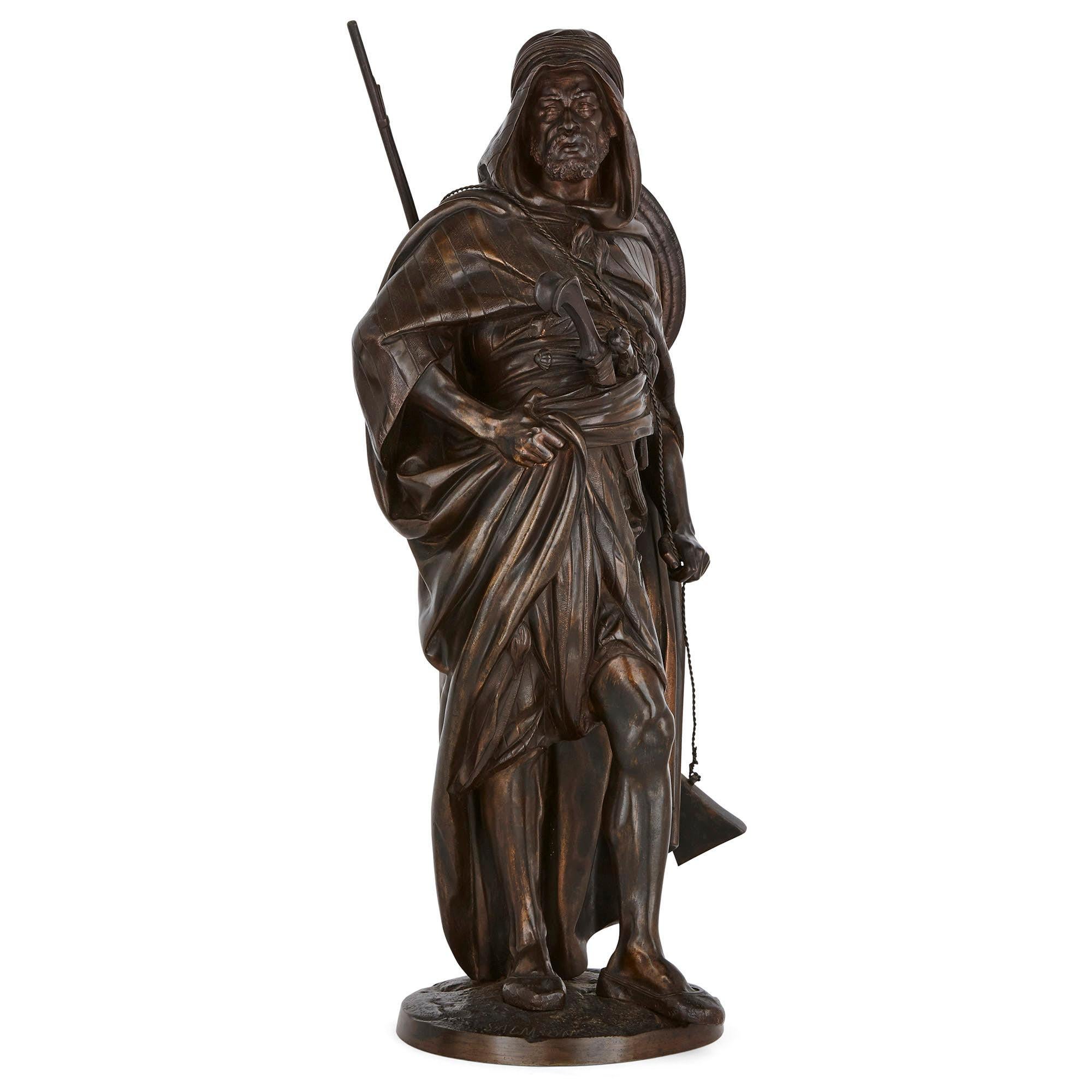 This pair of sculptures by Jean Jules Salmson, made of patinated bronze, depicts a male Arab warrior (‘Le Guerrier Arabe’) and a female water carrier (‘La Porteuse’). The male figure presents a dominant posture, his right elbow extending strongly