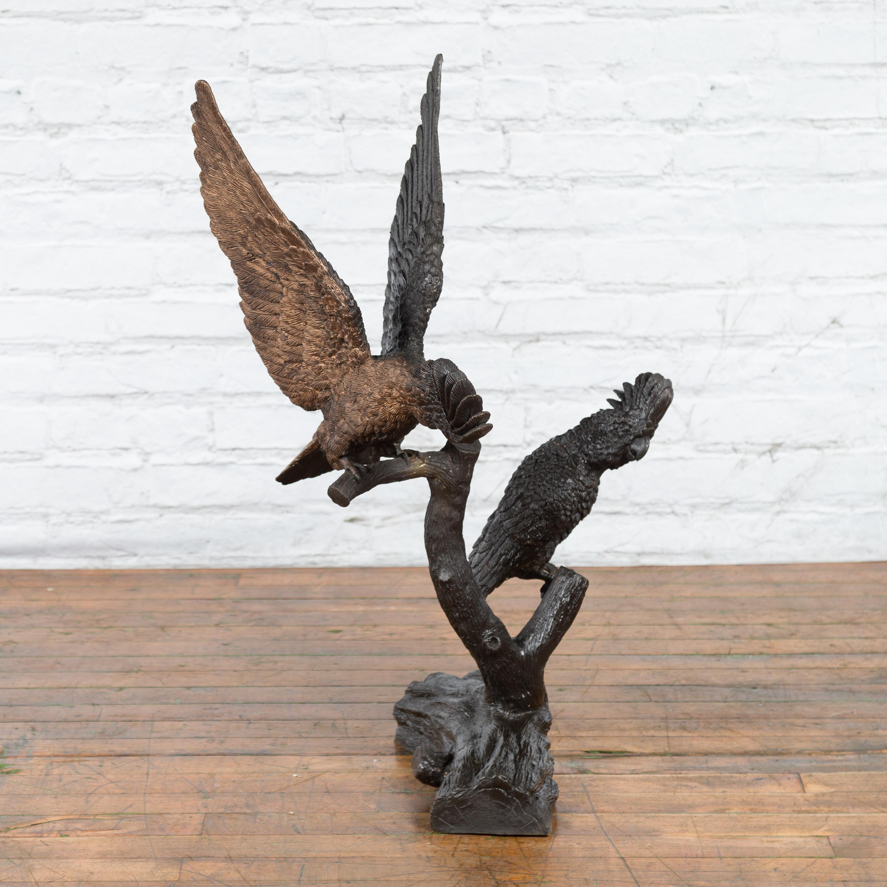 A contemporary lost wax cast bronze sculpted group depicting two parrots on a tree with hand-applied bronze and black patina. Created with the traditional technique of the lost-wax (à la cire perdue) which allows for great precision and finesse in