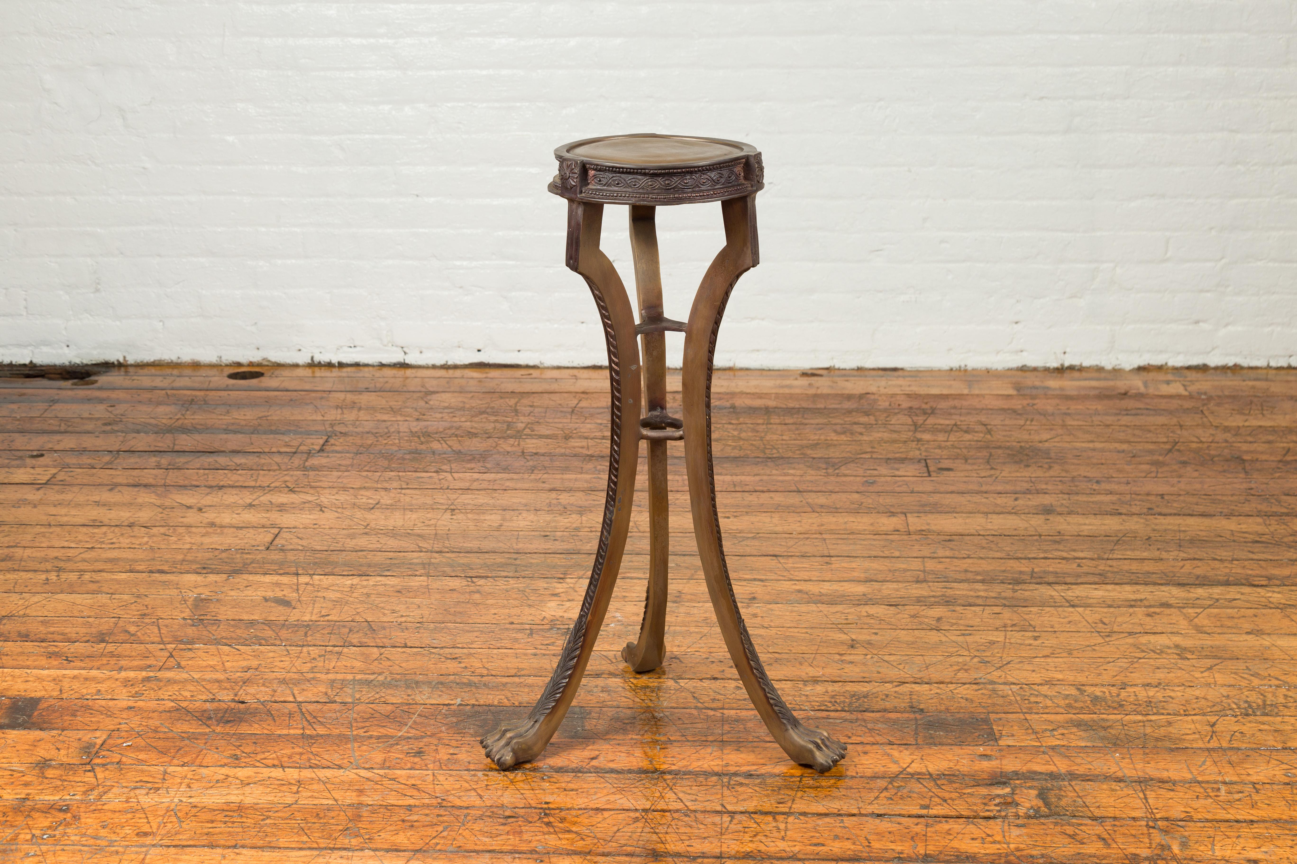 A bronze pedestal from the 20th century, with paw feet, meander frieze, rosettes and petite beads. Created with the traditional technique of the lost-wax (à la cire perdue) that allows a great precision and finesse in the details, this bronze