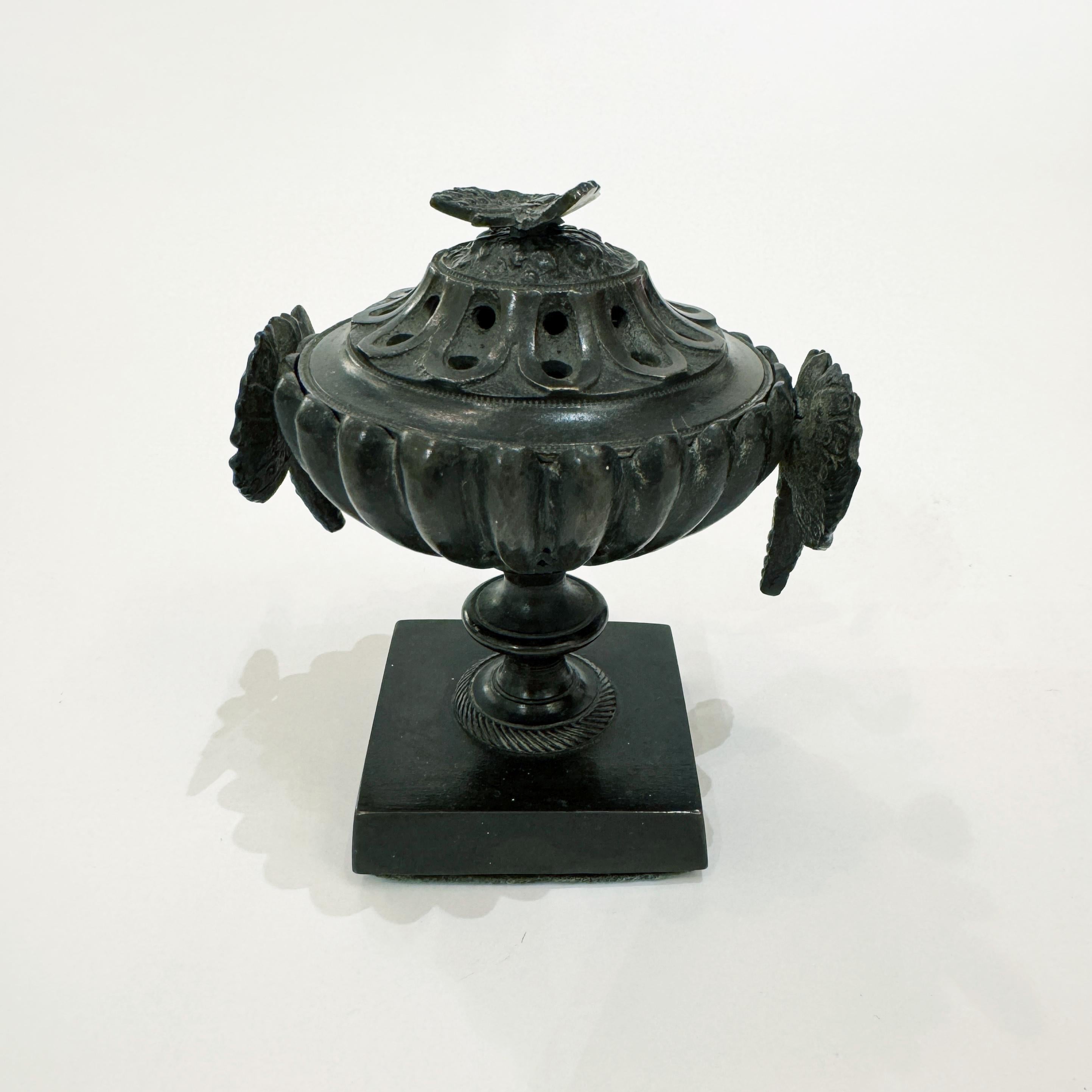 Parfumeur français en forme d'urne avec couvercle. Bronze patiné avec des papillons décoratifs sur un socle carré. France 1820
