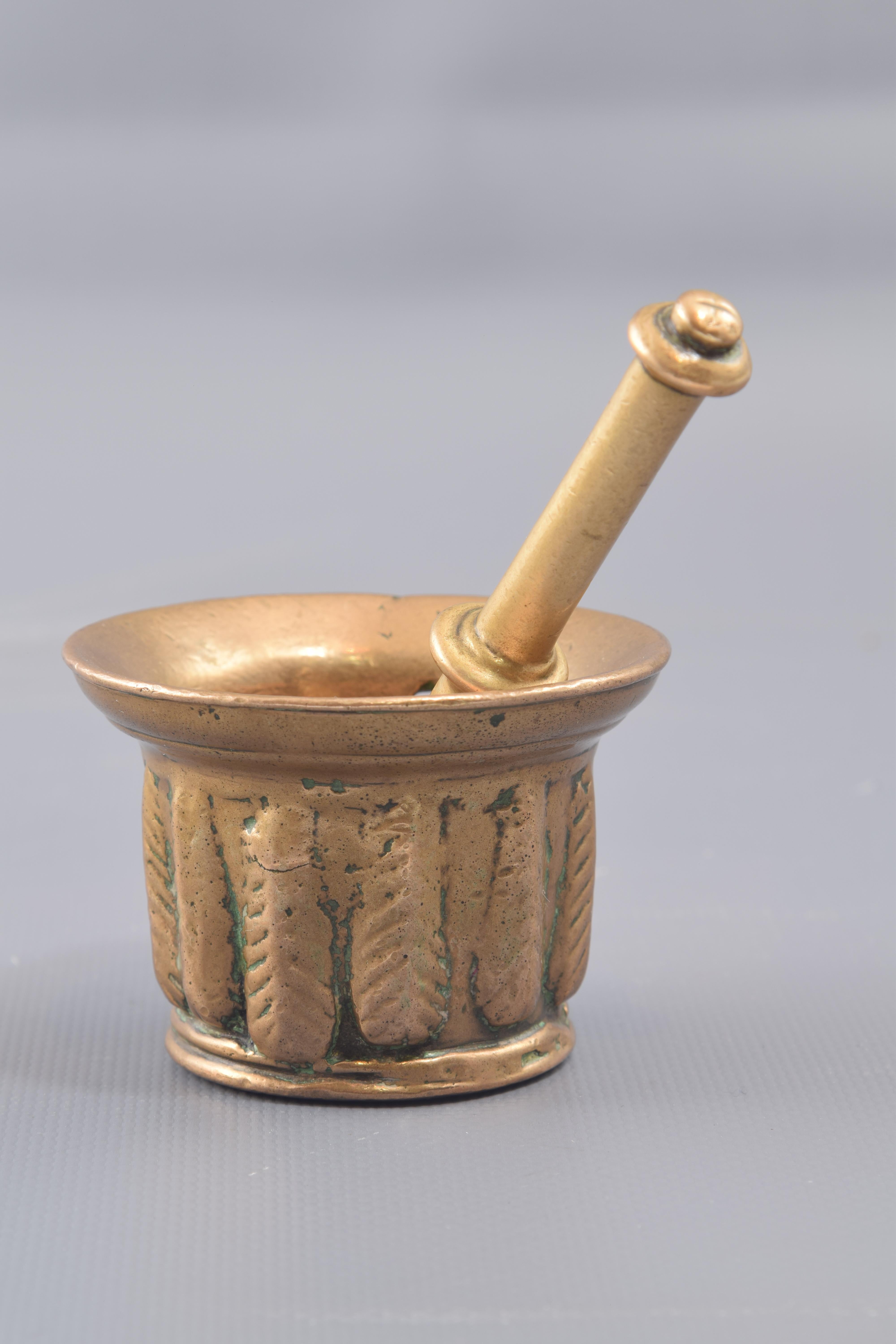 Poison mortar with mace. Bronze. Century XVI.
Small mortar with mace made of bronze, decorated with a band of vertical shapes that resemble leaves rather than ribs and this one with straight shaft widened at the end and a series of protruding