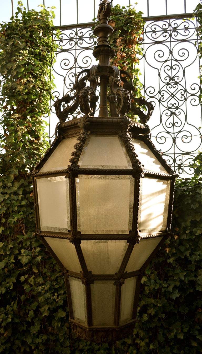 A monumental cast bronze and frosted glass porte cochere lantern; (a porte cochere is a roofed structure extending from the entrance of a building over an adjacent driveway and sheltering those getting in or out of vehicles). This example was likely