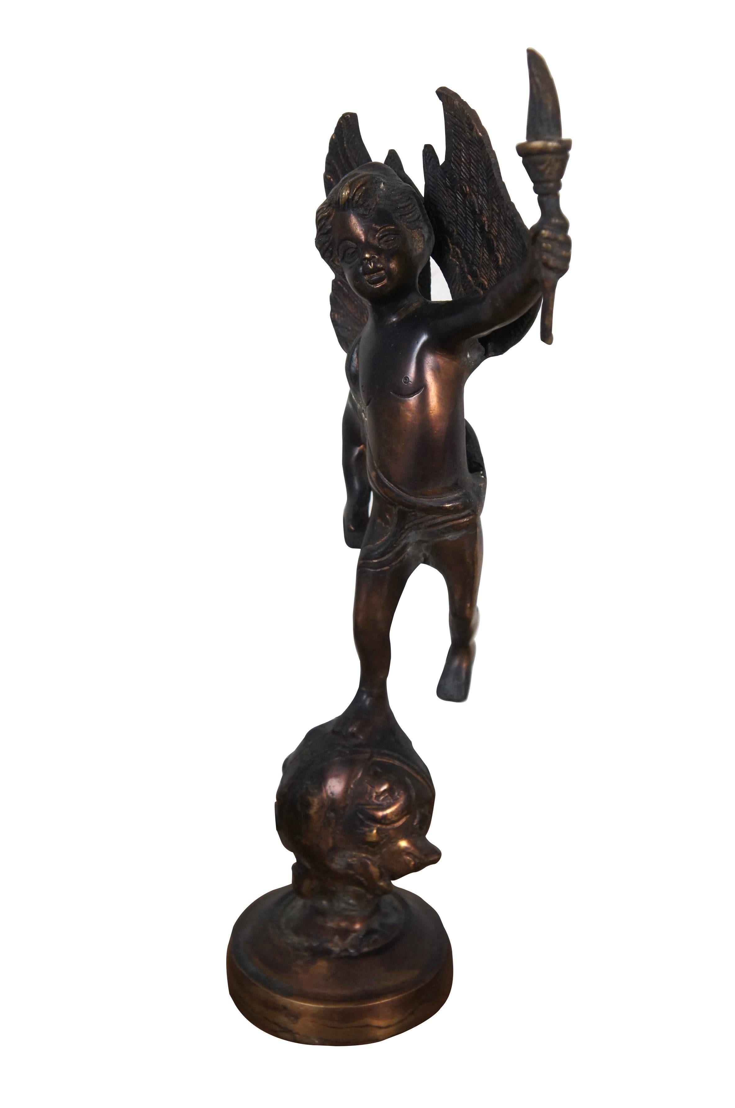 Vintage cast bronze sculpture / figurine in the shape of a putto / cherub / angel carrying a torch, perched on top of a globe studded with stars.

