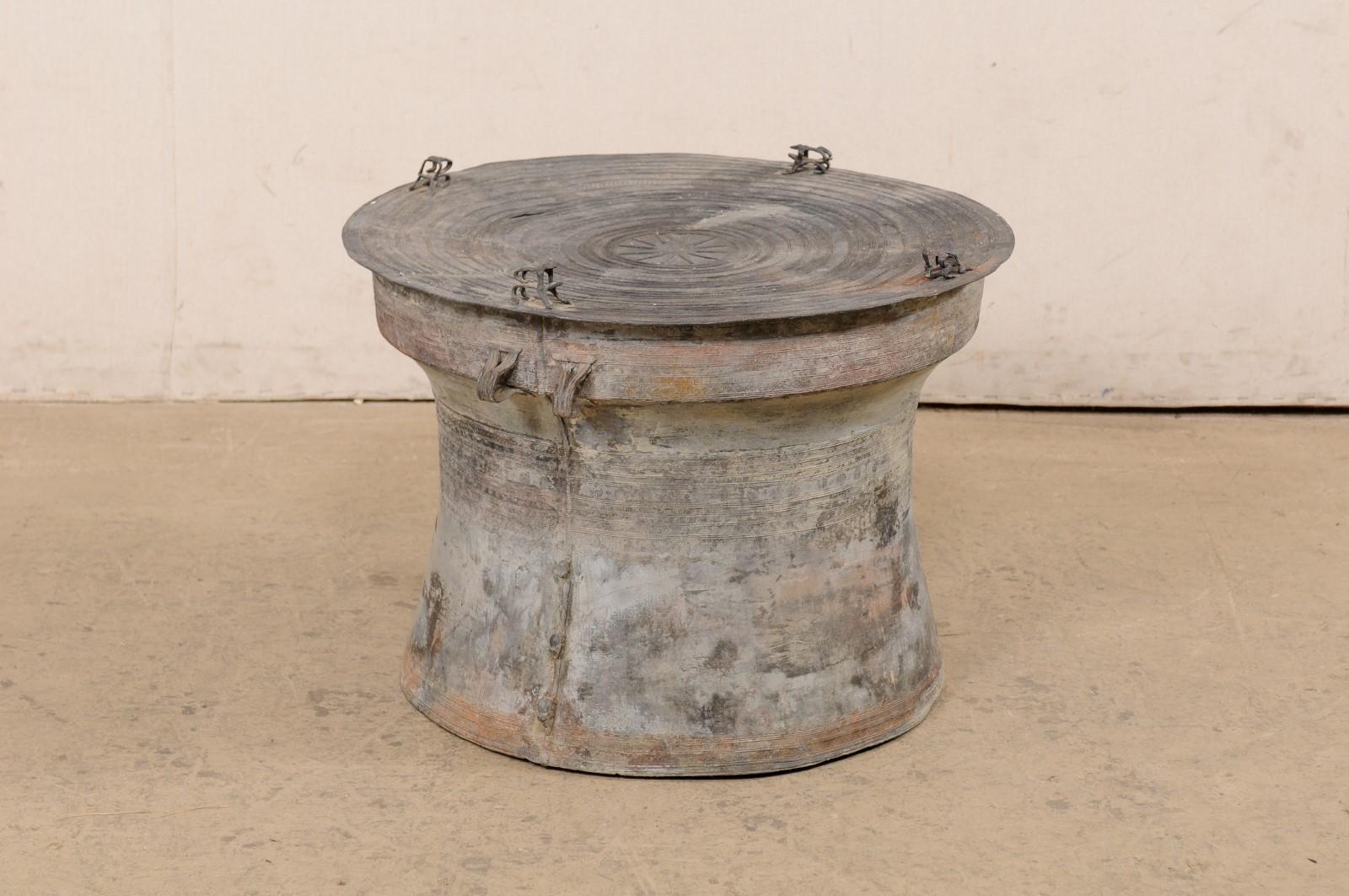 A Thai rain drum with sun and frog accents, from the mid 20th century. This vintage rain drum from Thailand, created from cast bronze, features a round-shaped top which is adorn with a sun at center, within concentric bands (said to represent the