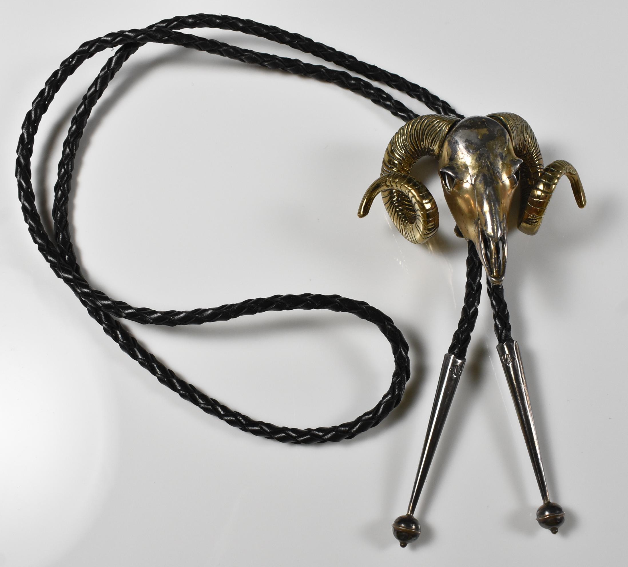 Un bolo unico nel suo genere, con testa di montone in bronzo e cordino in pelle nera. 2 1/4