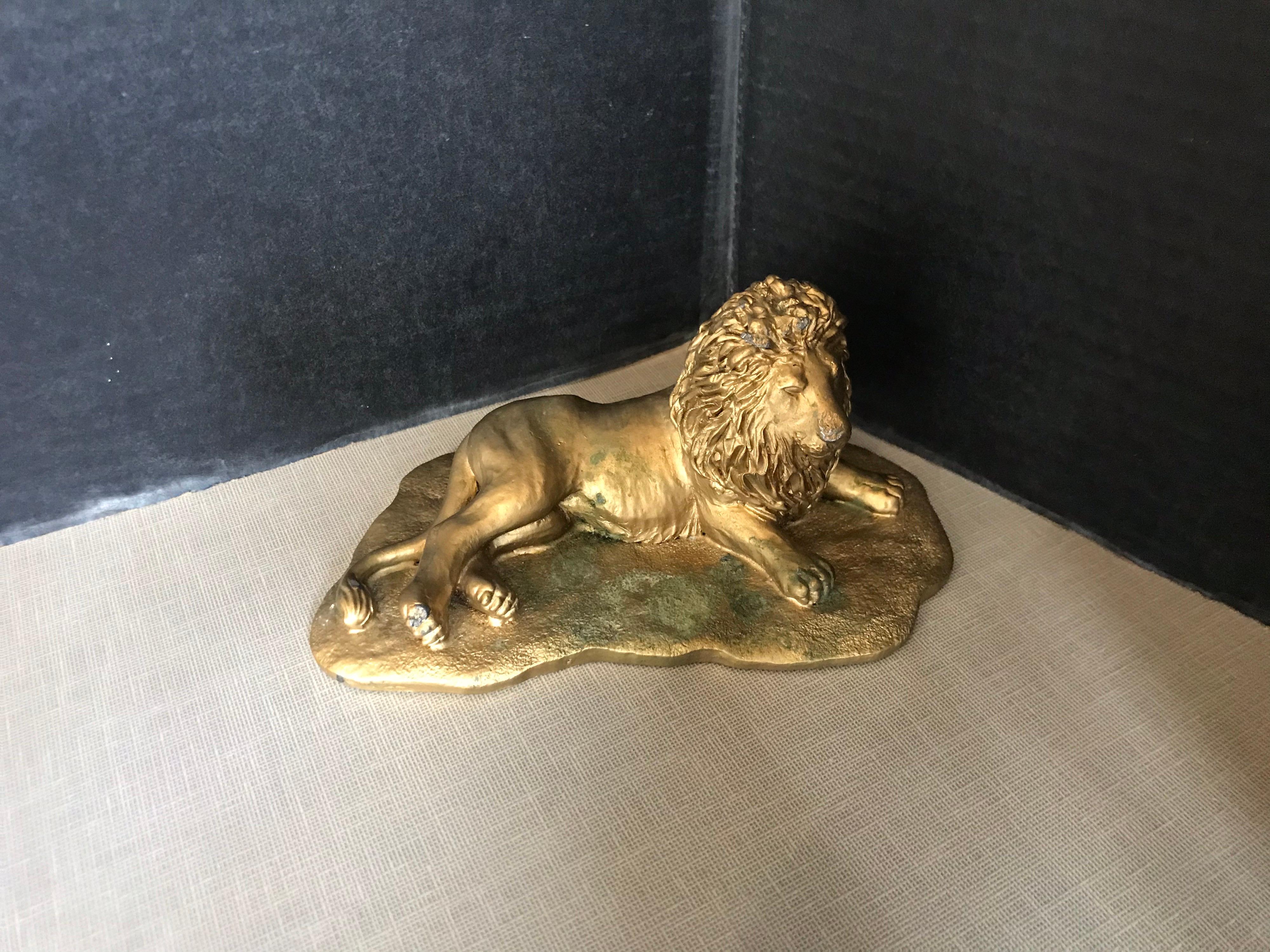 This is a heavy bronze gold painted reclining lion from the 1950s.