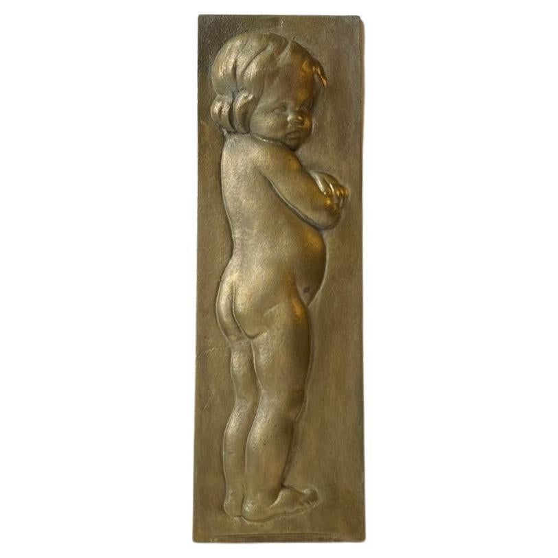 A stylized bronze wall relief depicting a naked infant girl. A hidden wall clasp allows you to install it anywhere suitable in the room. It was made on order in Scandinavia, probably in Copenhagen, Denmark, during the 1930s. Its a heavy solid bronze