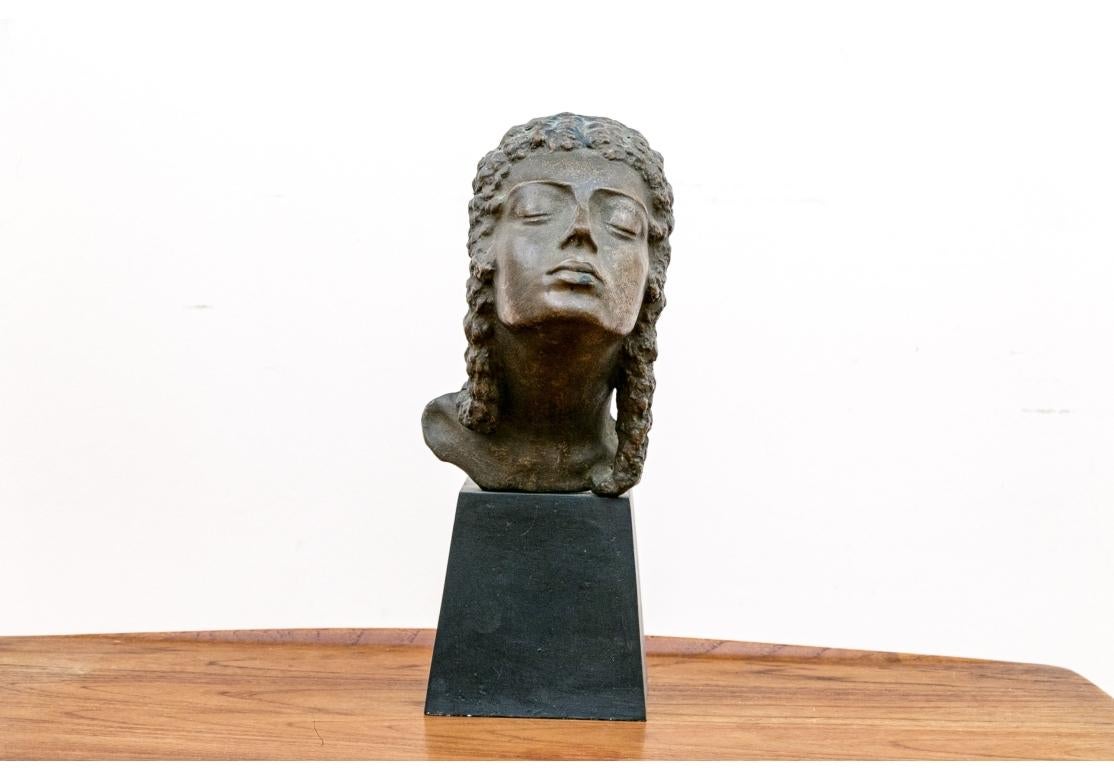 Bronze resin sculpture depicting a Classical type female having long braided hair with her eyes closed. The piece is not signed. Acquired originally in London at the Fieldborne Galleries in 1979. 
Mounted on a ebonized wood plinth.

Dimensions: 5