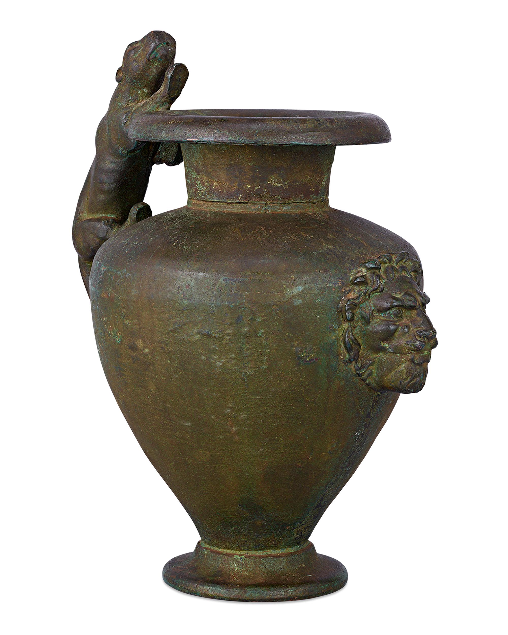This extremely rare oenochoe, or wine jug, dates to the 2nd century CE. Crafted of bronze with an exquisite green patina, the sculpted handle is in the shape of a lioness, while the body is decorated with a lion's head and rests on a sculpted round