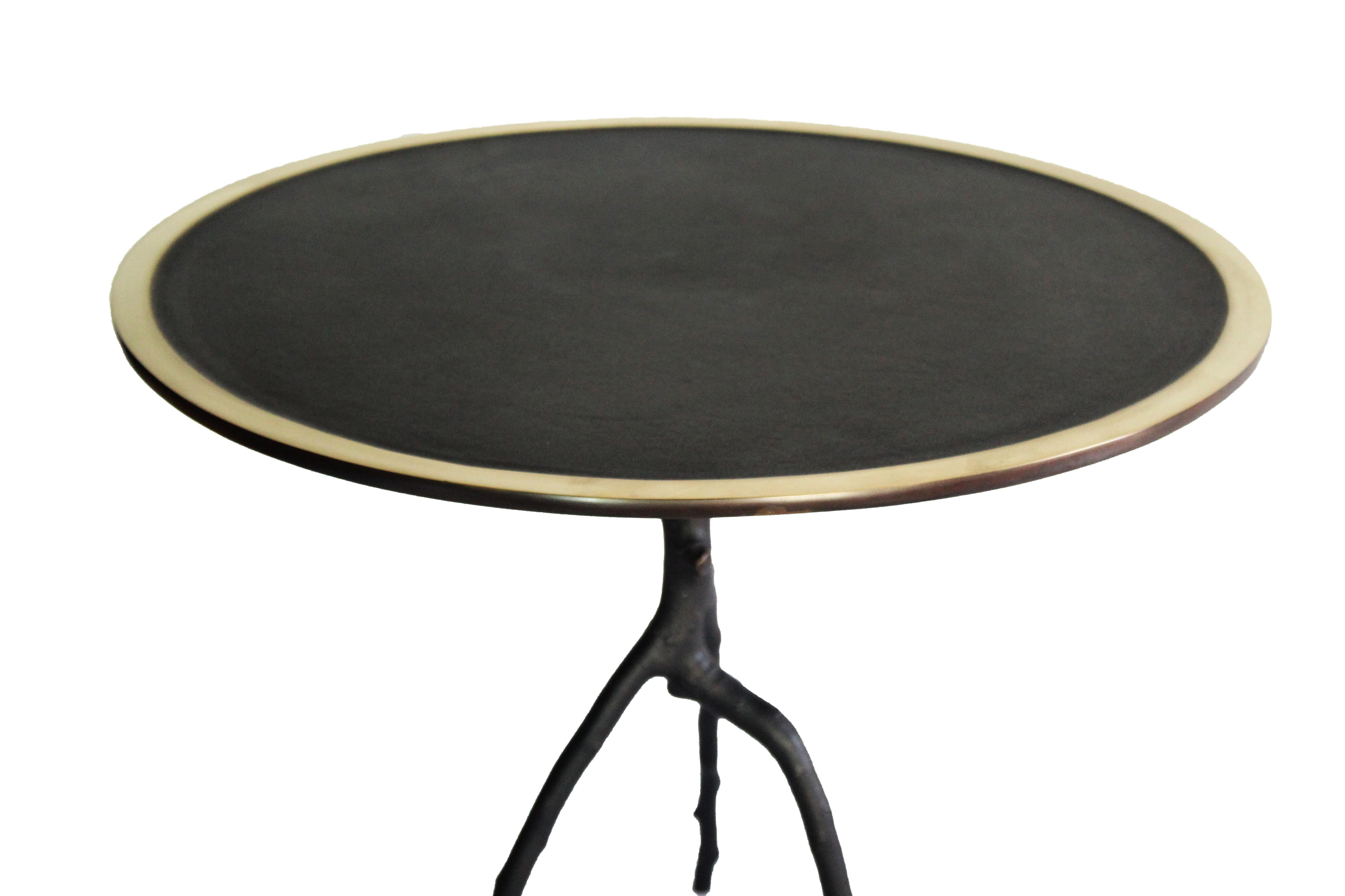 Cette table basse artisanale est fabriquée en France. Avec une branche de pommier en guise de pied et un plateau rond au contour poli, cette table d'appoint est patinée en noir. Chaque table d'appoint est signée et numérotée. Cette table d'appoint