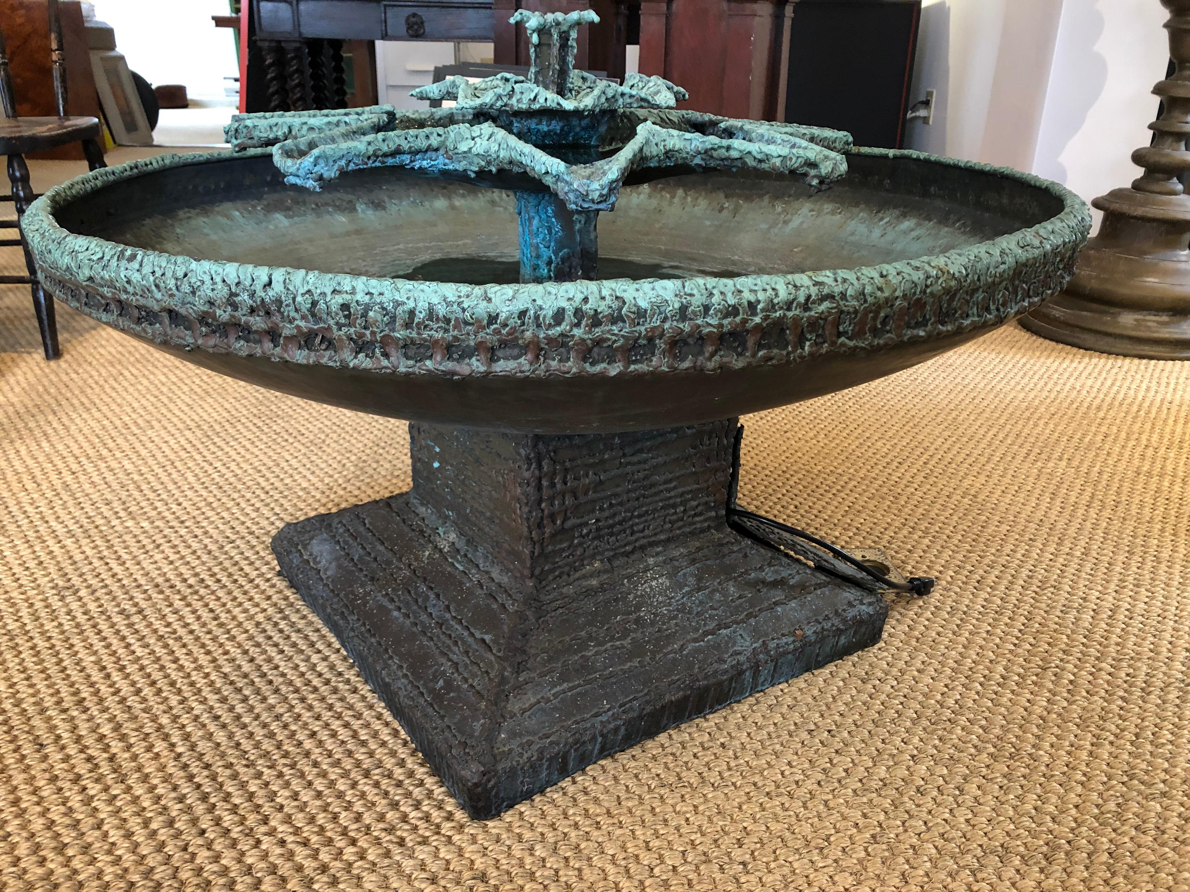 A modernist, yet classical, bronze fountain, made by California-based artist Aristides (Aris) Demetrios, circa 1970. Water issues from the center and cascades down the the two-tiered star shaped elements into an elegant circular bowl below,