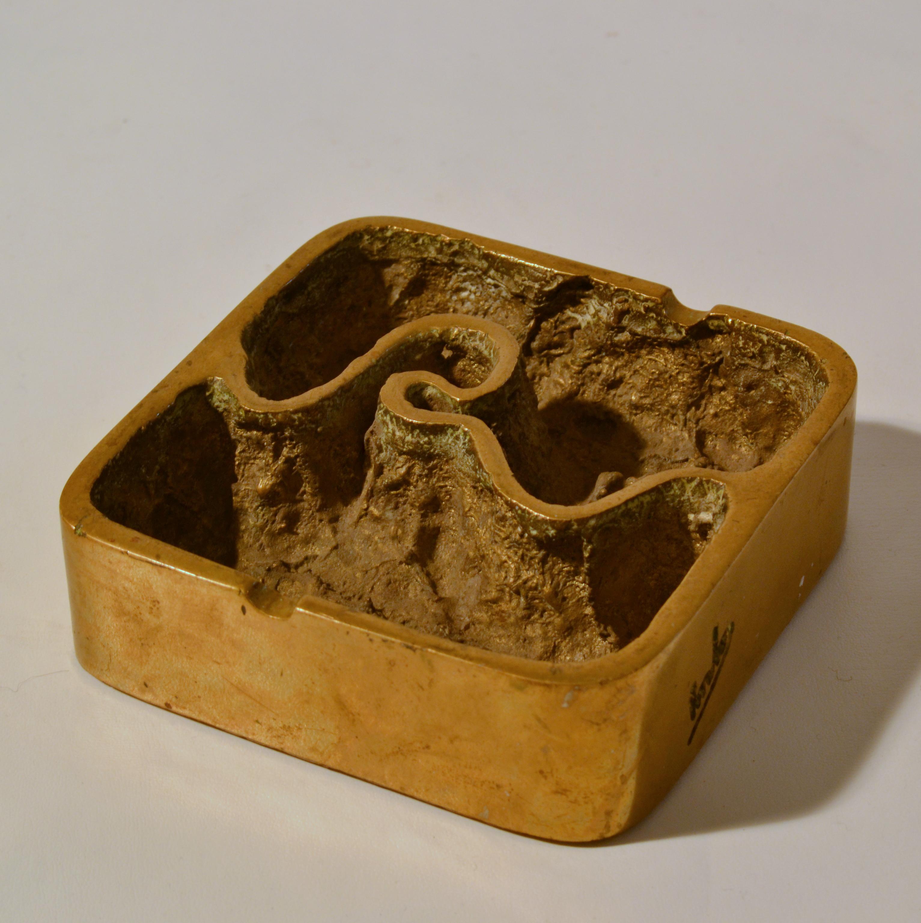 Hand-sculpted and bronze cast ashtray or paper weight is made in the 1970s and is signed. The shape is square and the pattern looks like a river that finds its natural way through a textured patinated landscape.