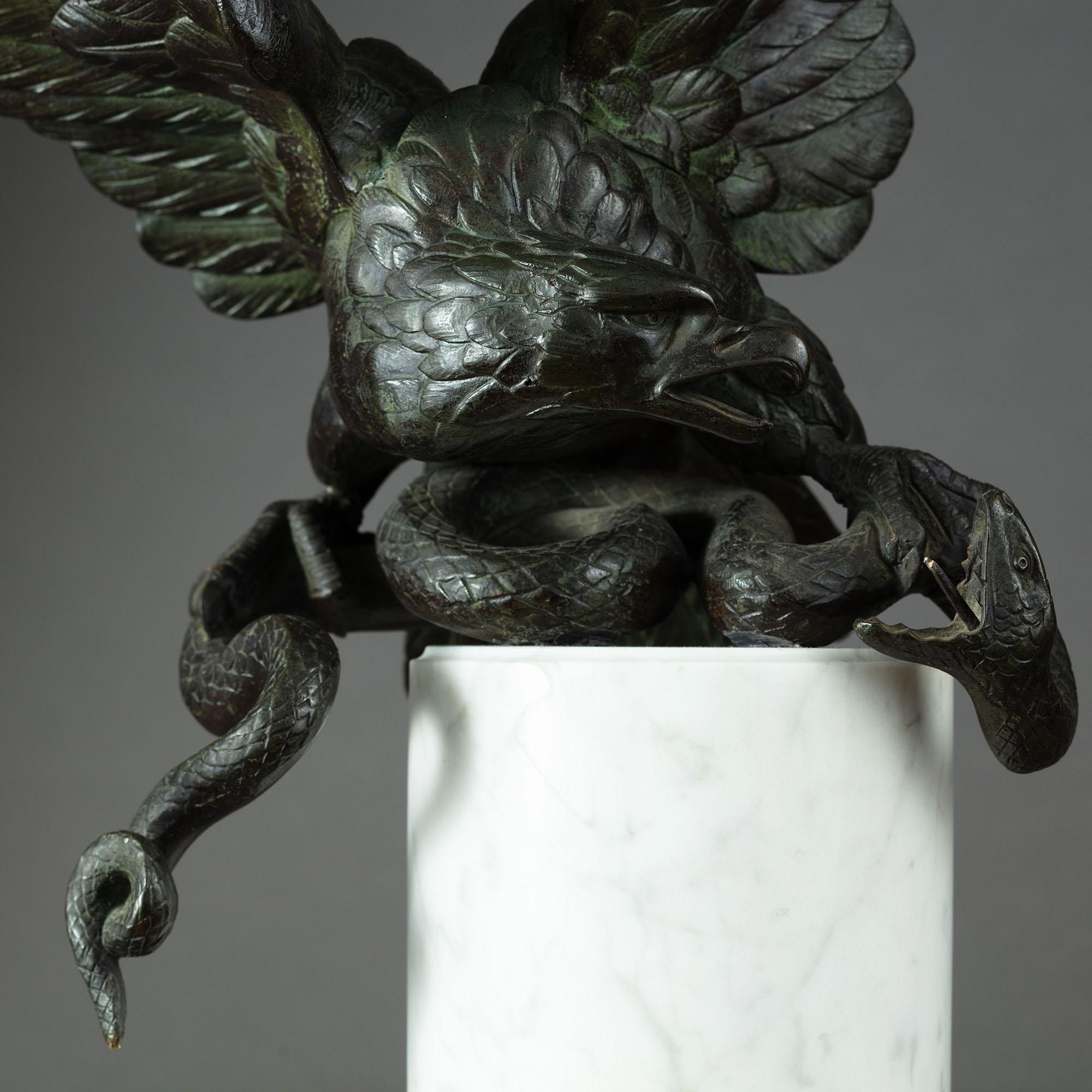 19th century bronze bird of prey fighting a serpent mounted on a white marble pedestal.

Dimensions: Height 15.75? x width 13? x depth 8?.