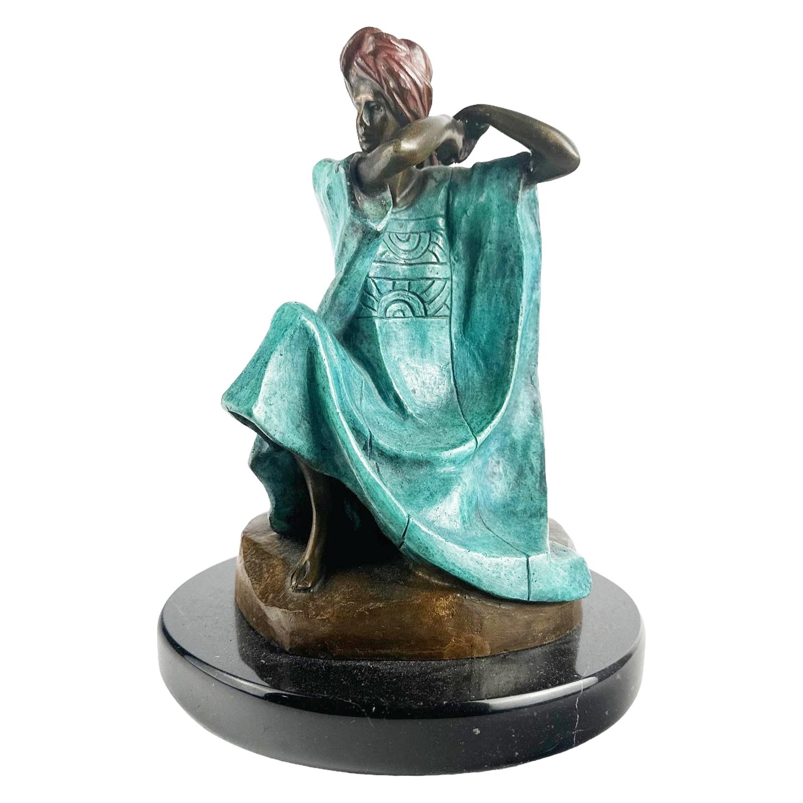 Victor Gutierrez (Mexican, born 1950). A limited edition cold painted bronze statue. A figural work produced in a modern style depicting a seated female figure in traditional Mestizo style costume, with a red turban, modeled on a Modernist base.