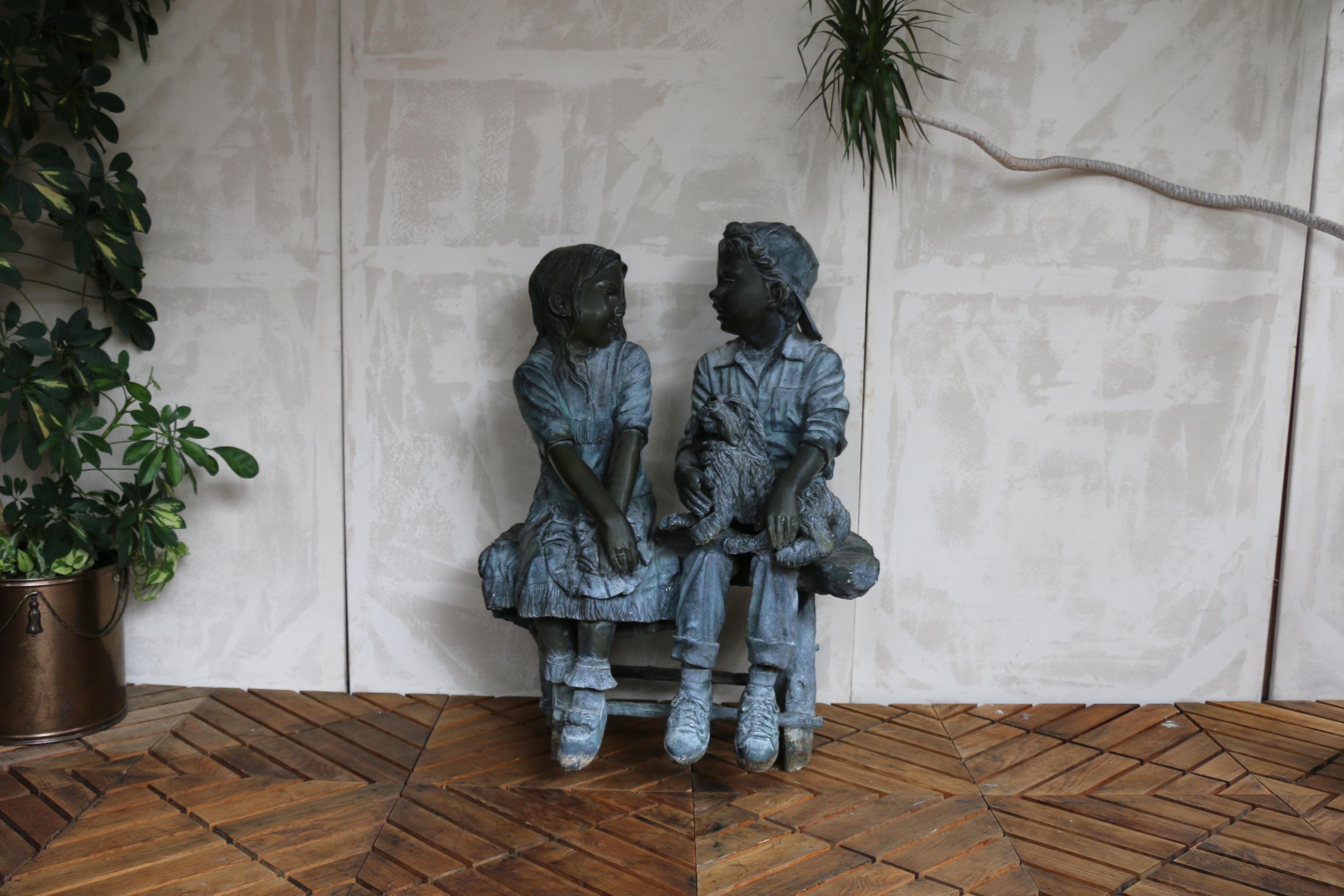 Splendida scultura in bronzo disegnata dall'artista americano Jim Davidson (c'è la firma dell'autore). Questa incantevole statua raffigura un ragazzo e una ragazza seduti su una panchina con un cane, un tema molto popolare per l'arredamento di