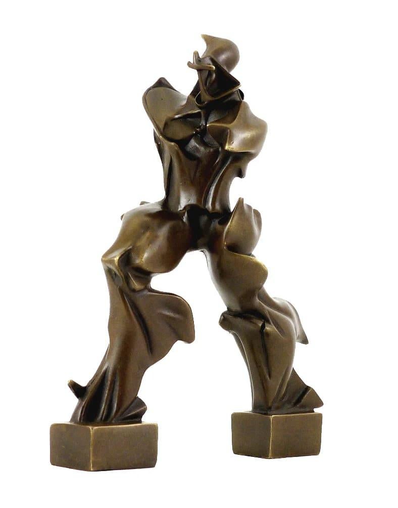 Cette sculpture en bronze célèbre la vitesse, le mouvement et la fusion de l'homme avec la technologie moderne.
La forme humaine est transformée en lignes fluides et aérodynamiques qui traduisent un mouvement vers l'avant imparable. Sa modélisation