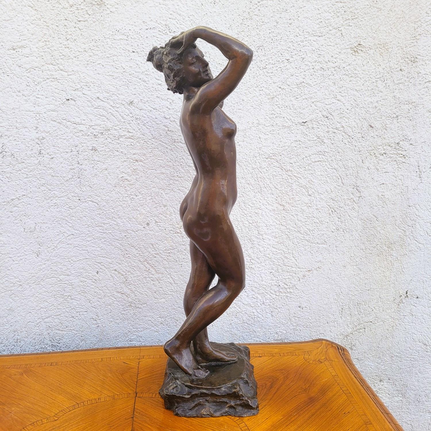 Bronze with brown patina of a nude woman, standing, putting up her hair.   

Wear and tear on the patina.   

circa 1900

Height 56.5cm.  
20 x 15cm.