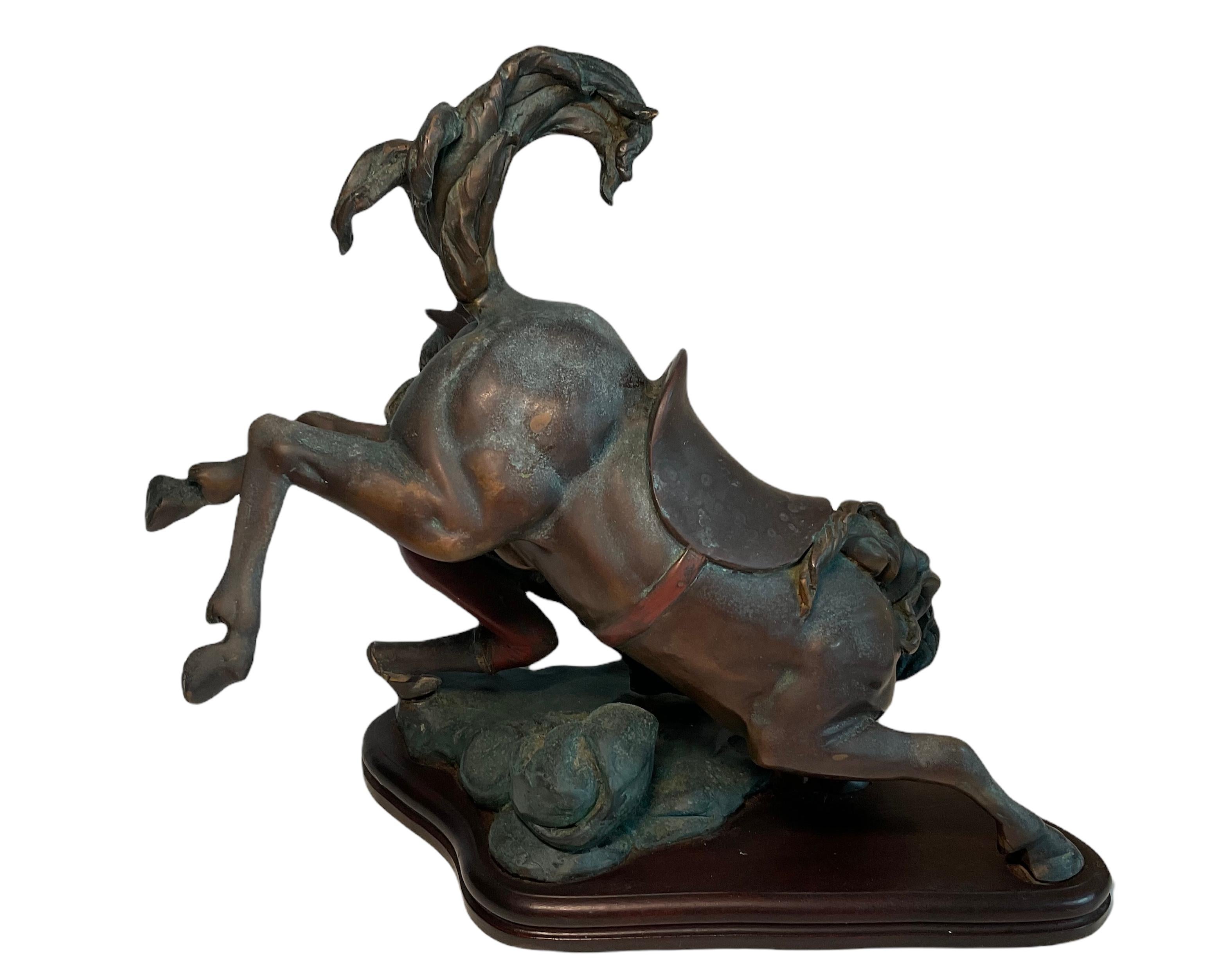 This is a rare and very well done bronze sculpture depicting a cowboy who is standing in the soil and has finally conquered a bucking horse in a rodeo. The clothes of the bronze cowboy and the saddle back billet are painted. The mane and tail almost