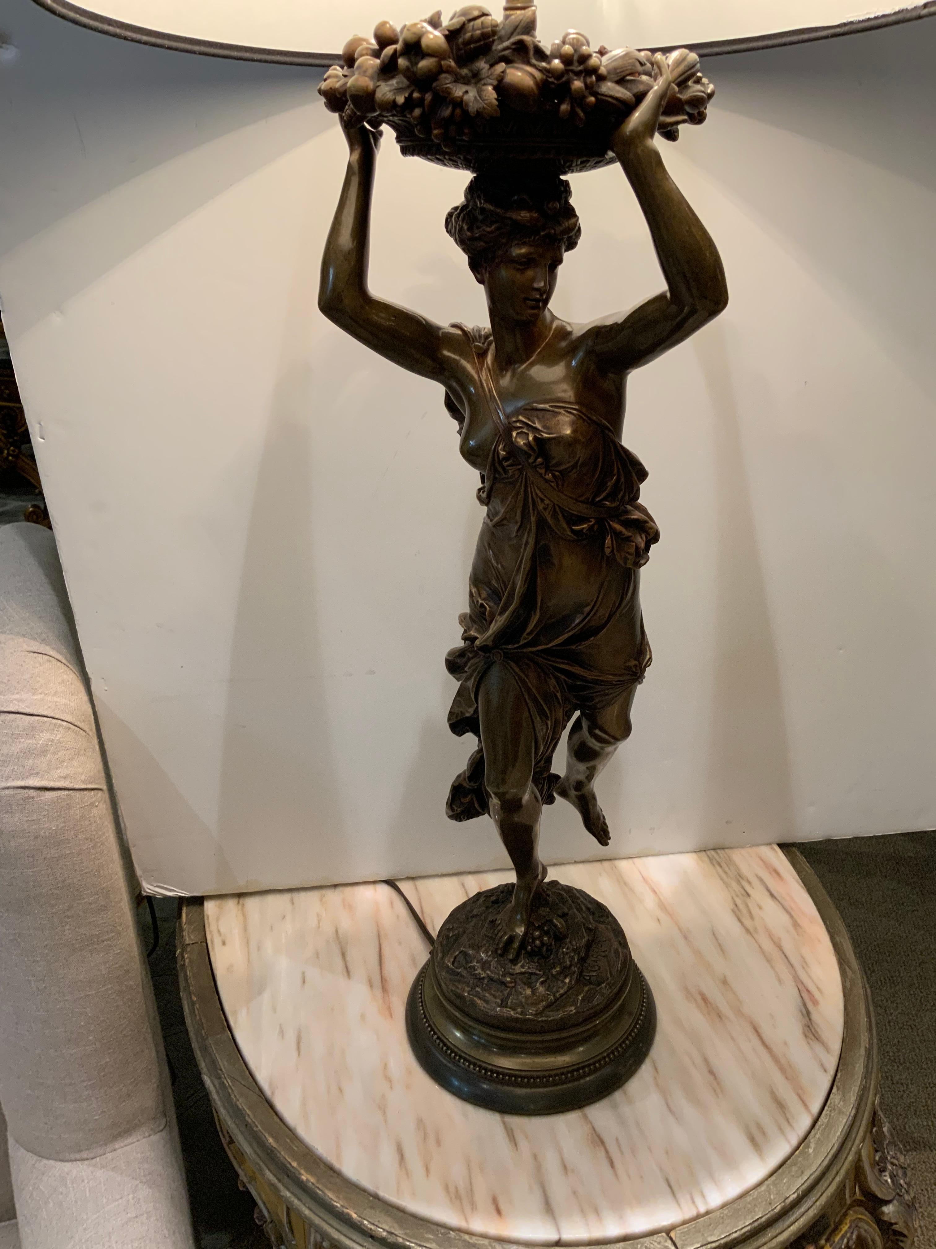 Sculpture of a woman in bronze carrying a basket of fruit over her head. The bronze is signed
At the base A. Carrier. Graceful sculpture with exquisite lines, mounted as a lamp.