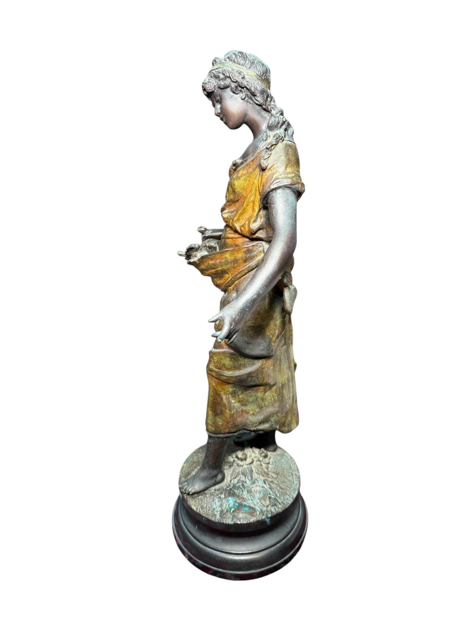 Si tratta di una scultura in bronzo di una ragazza di August Moreau. Raffigura una scultura in bronzo dipinta di una giovane contadina che indossa un abito giallo ed è a piedi nudi. Ha i capelli ricci ornati da una fascia gialla. Sta raccogliendo