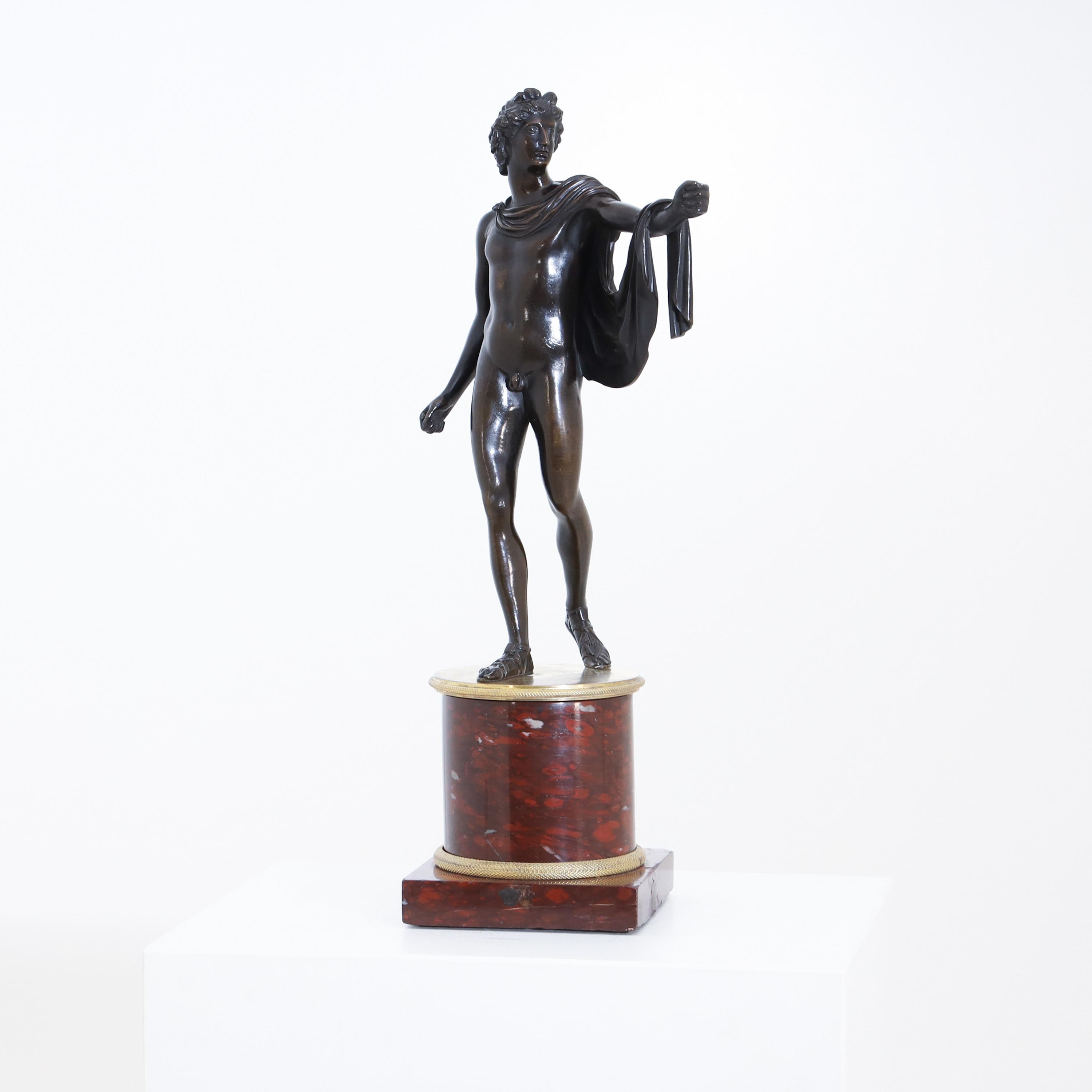 Bronze figure of Apollo Belvedere standing on a red marble base with fire-gilded profiles. Early French work after the famous original, which was in the Louvre at the time, due to Napoleon's Italian campaign (1798-1815).