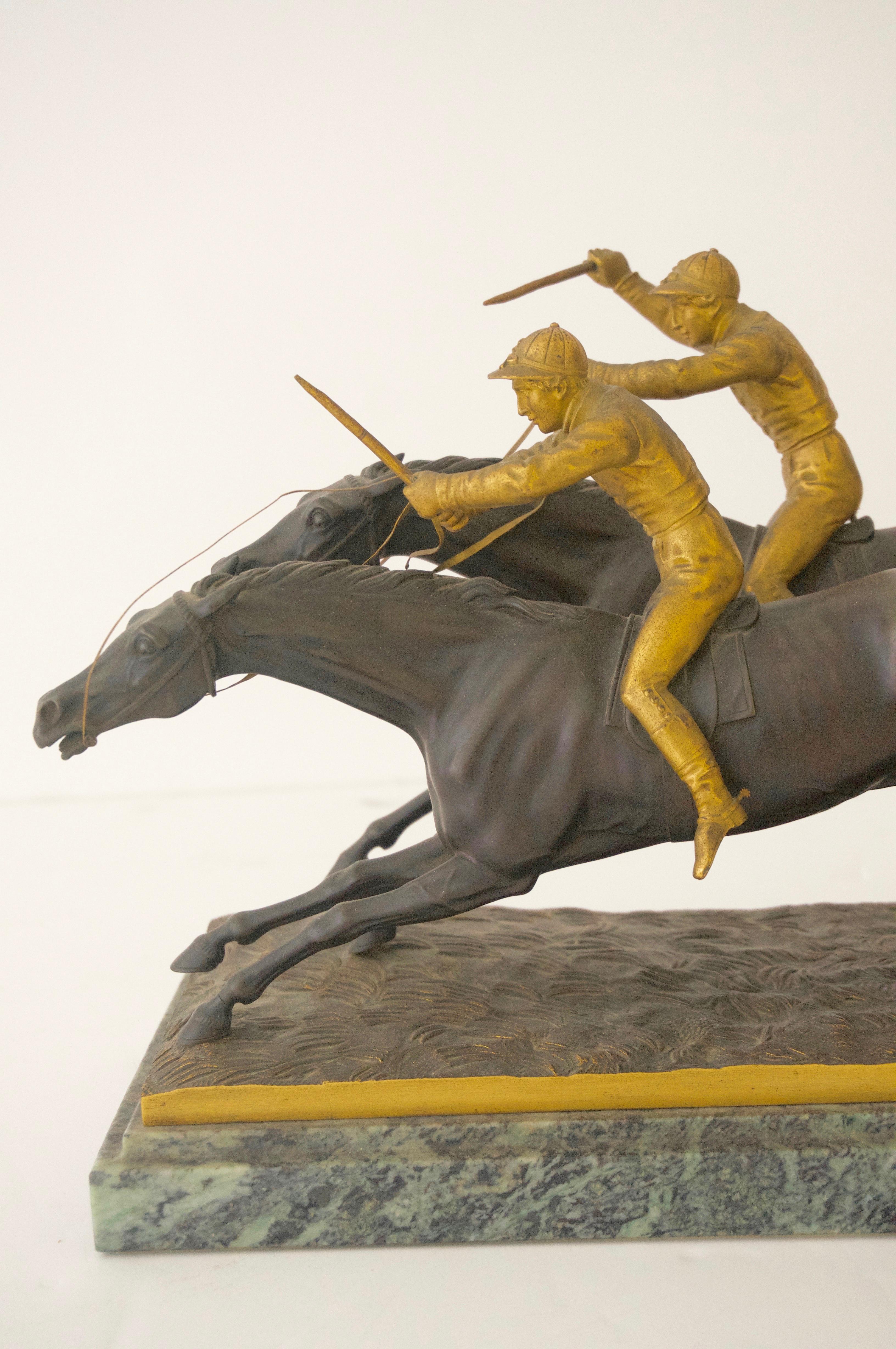 This classic and styish Edwardian sculpture depicts the climactic moment of the finish-line as the horses are neck and neck...

 The dark bronze of the horses is accented with the gilded bronze jockeys, all of which are mounted on a verdi green