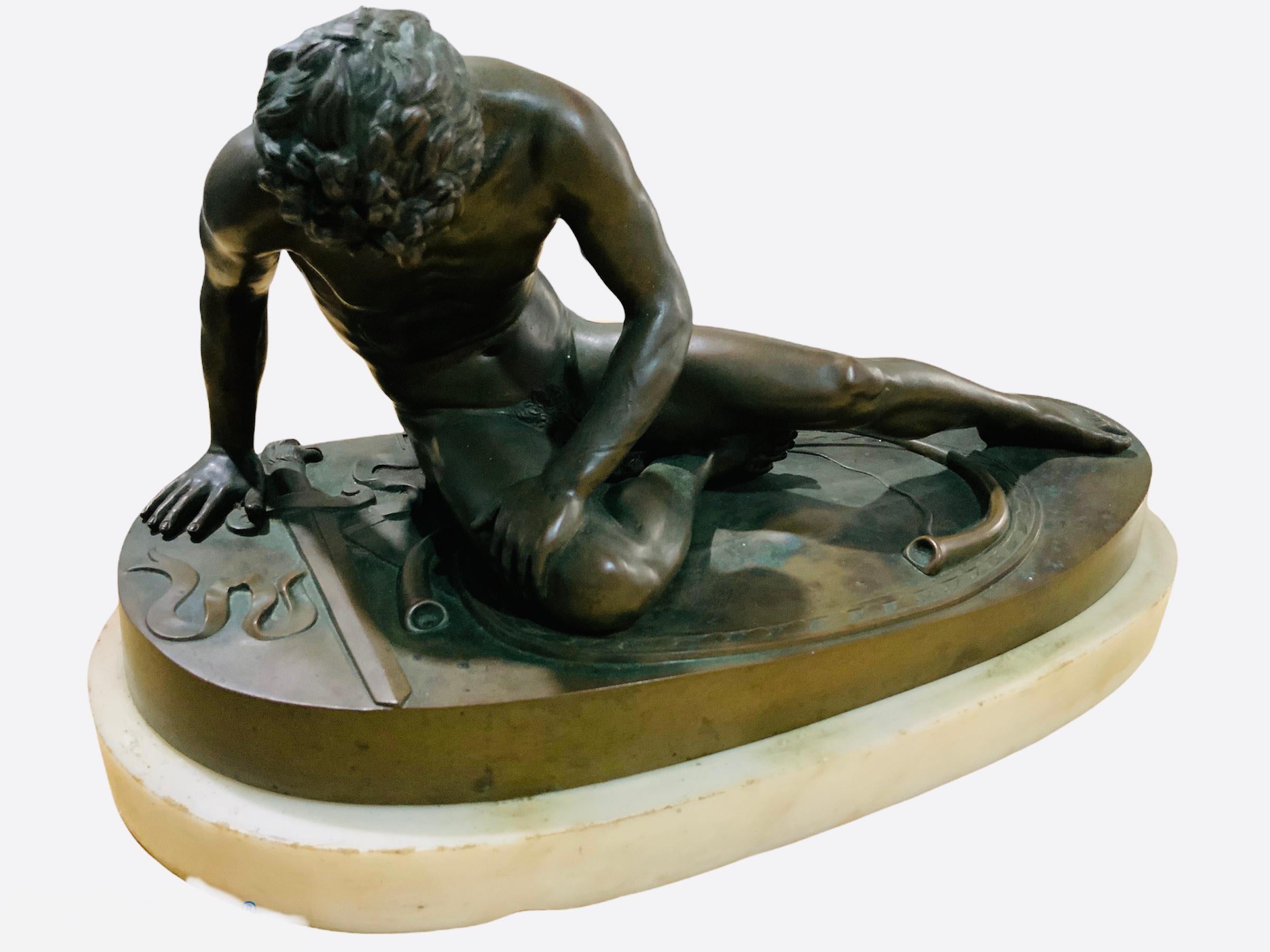 This is a bronze sculpture of The Dying Gaul. It depicts a young nude gladiator seated in the ground and leaning in his right hand after being wounded in the chest. He has abundant hair and his face show the pain that he is suffering. His sword,
