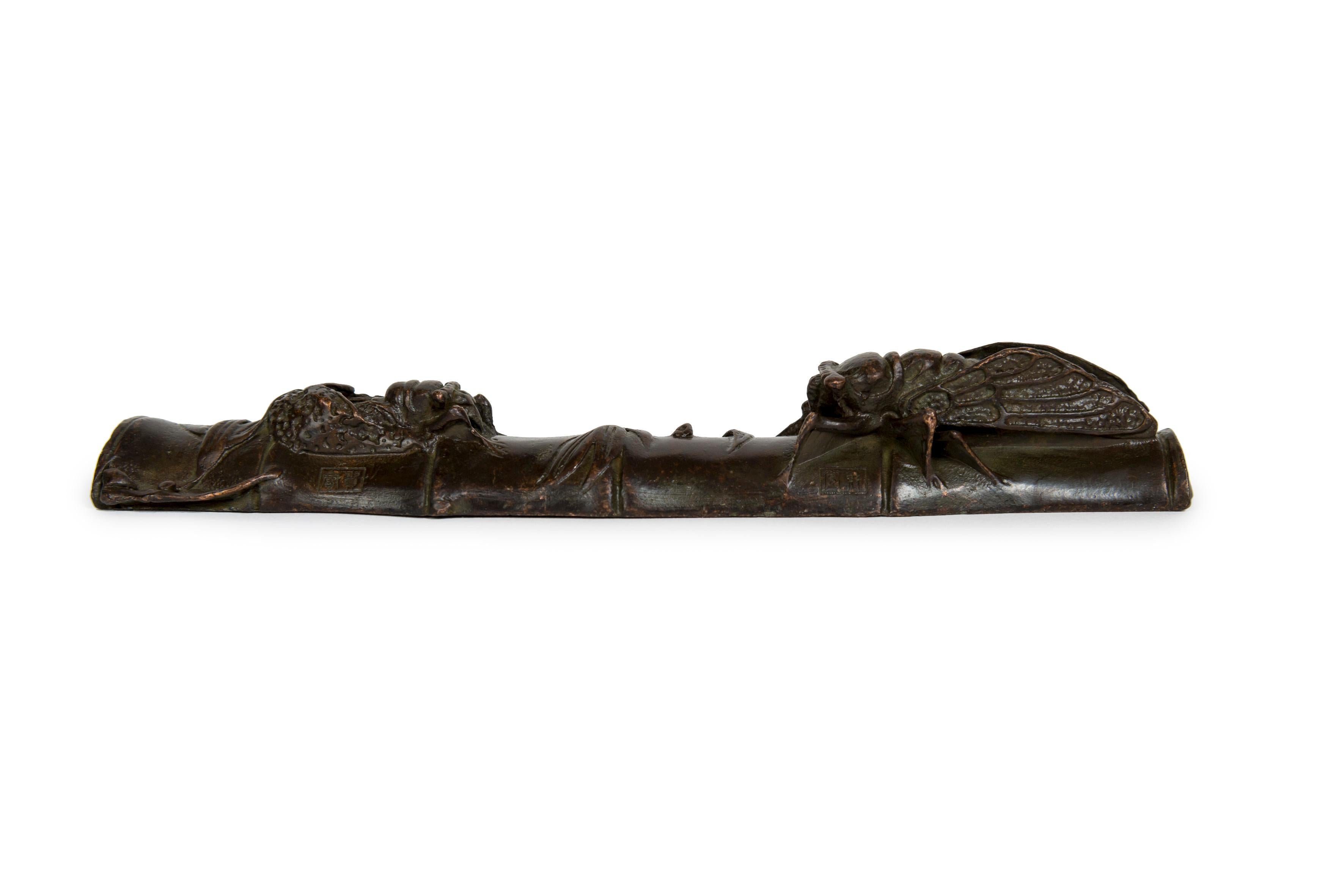 Due Cicada in bronzo che si fronteggiano su un segmento di bambù

Uno è un adulto mentre l'altro è in fase di ninfa. Tre timbri di fonderia, uno sotto e uno accanto a ciascun insetto.
Le Cicada hanno un ruolo molto importante nel folklore