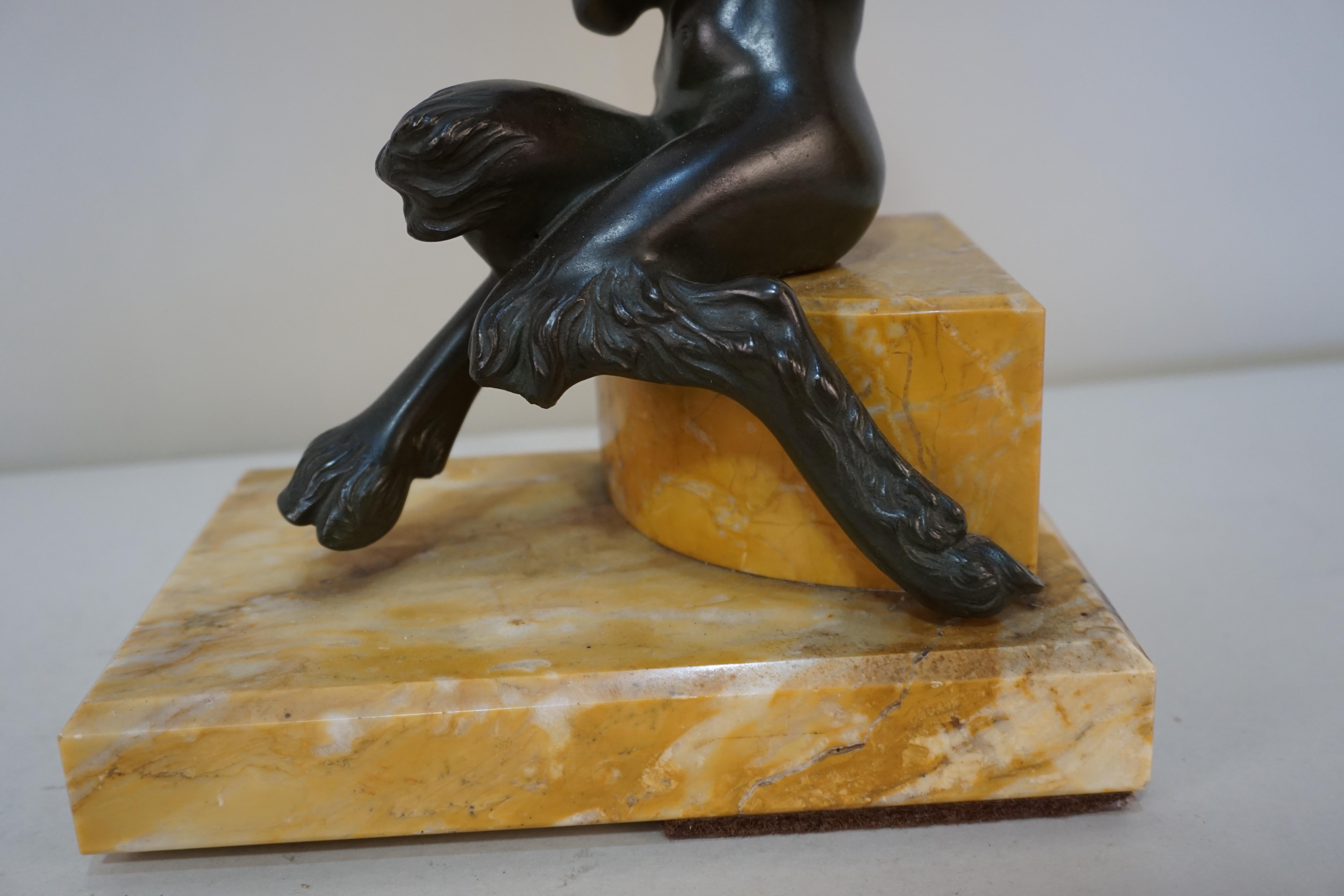 Bronze sculpture of young man playing a flute. Dark brown or green patina with marble base.