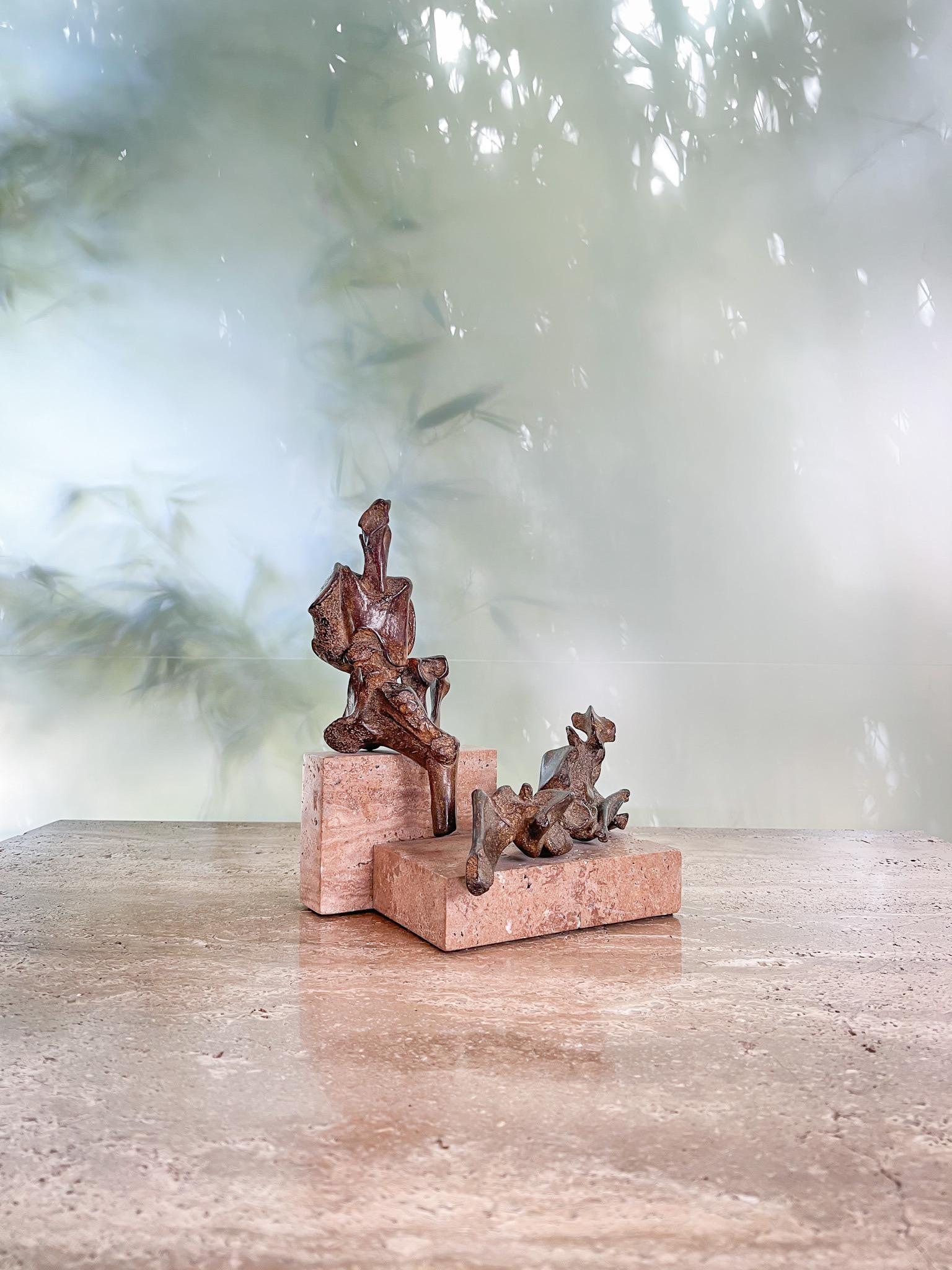 A wonderful pair of figurative abstract bronze sculptures on travertine bases by James Edward Ritchie, 1987. The sculptures are affixed to the base as one unit. Beautiful patina.