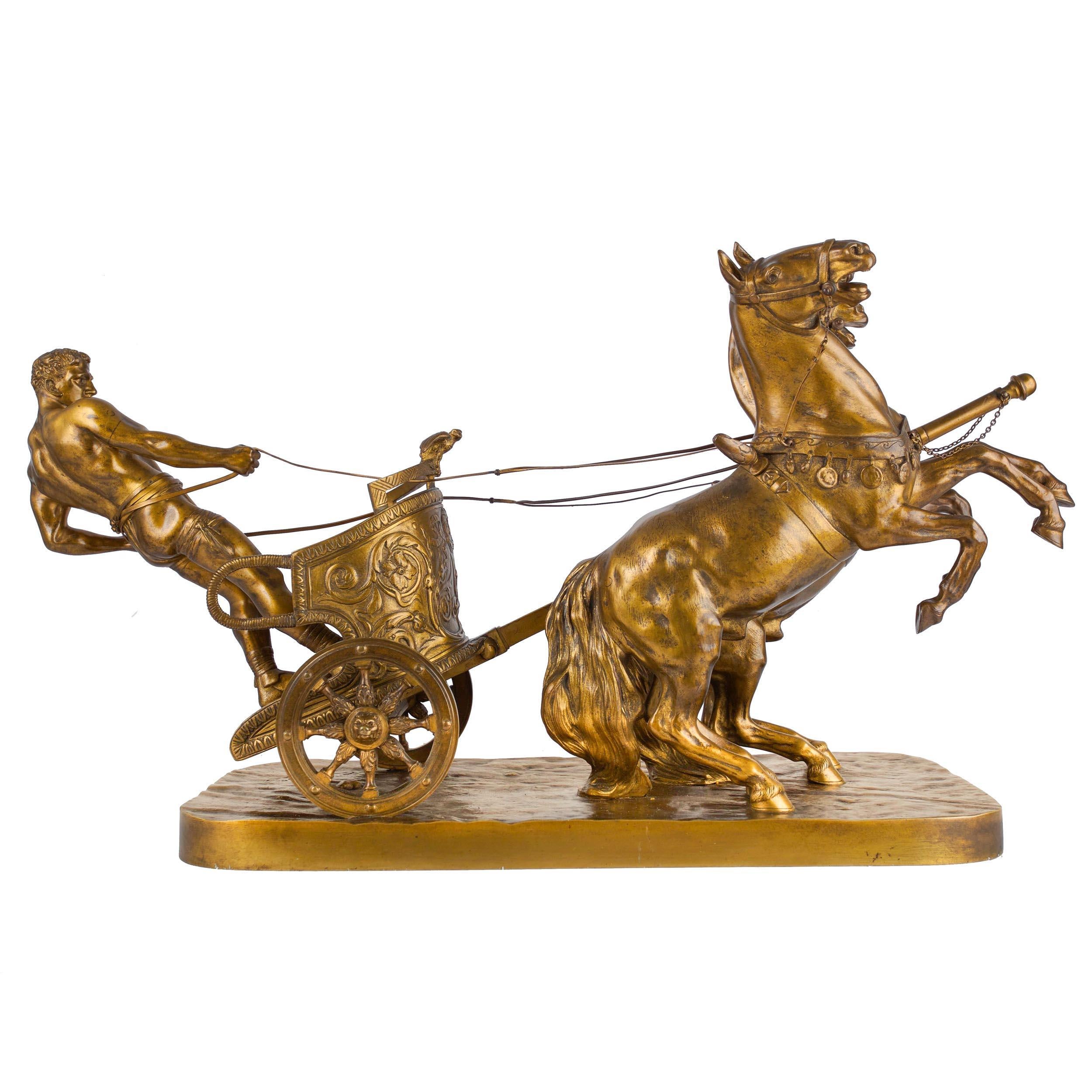 A powerful bronze group executed in a gilt and burnished surface, this model of Roman Charioteer is one variation modeled by Arthur Strasser with the man driving a group of two horses; he also made a larger version with the charioteer driving four