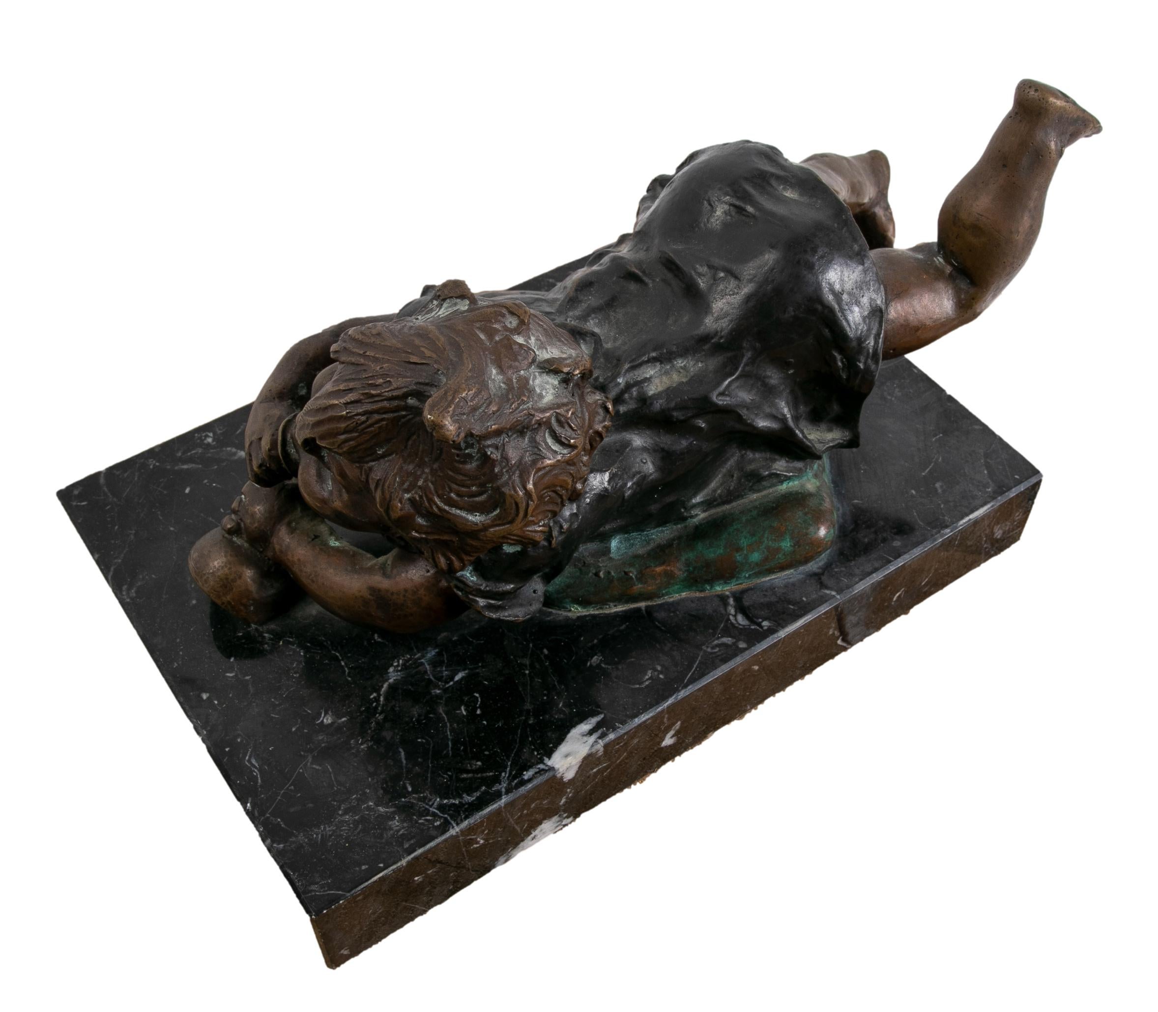 Bronze sculpture with marble base of a little girl lying down.