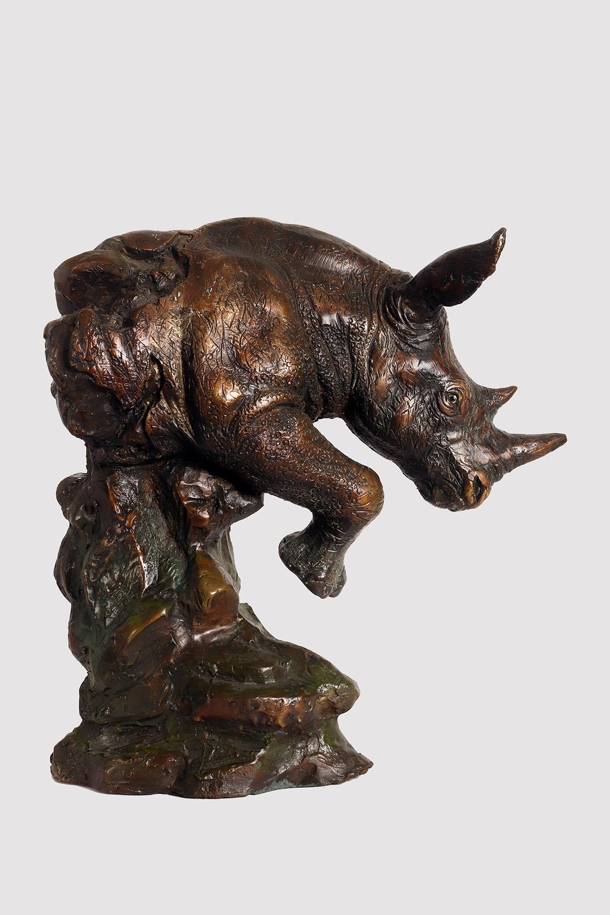 Sculpture en bronze coulé représentant un rhinocéros émergeant du rocher avec une jambe levée. Yeux en pâte de verre. France 1900.