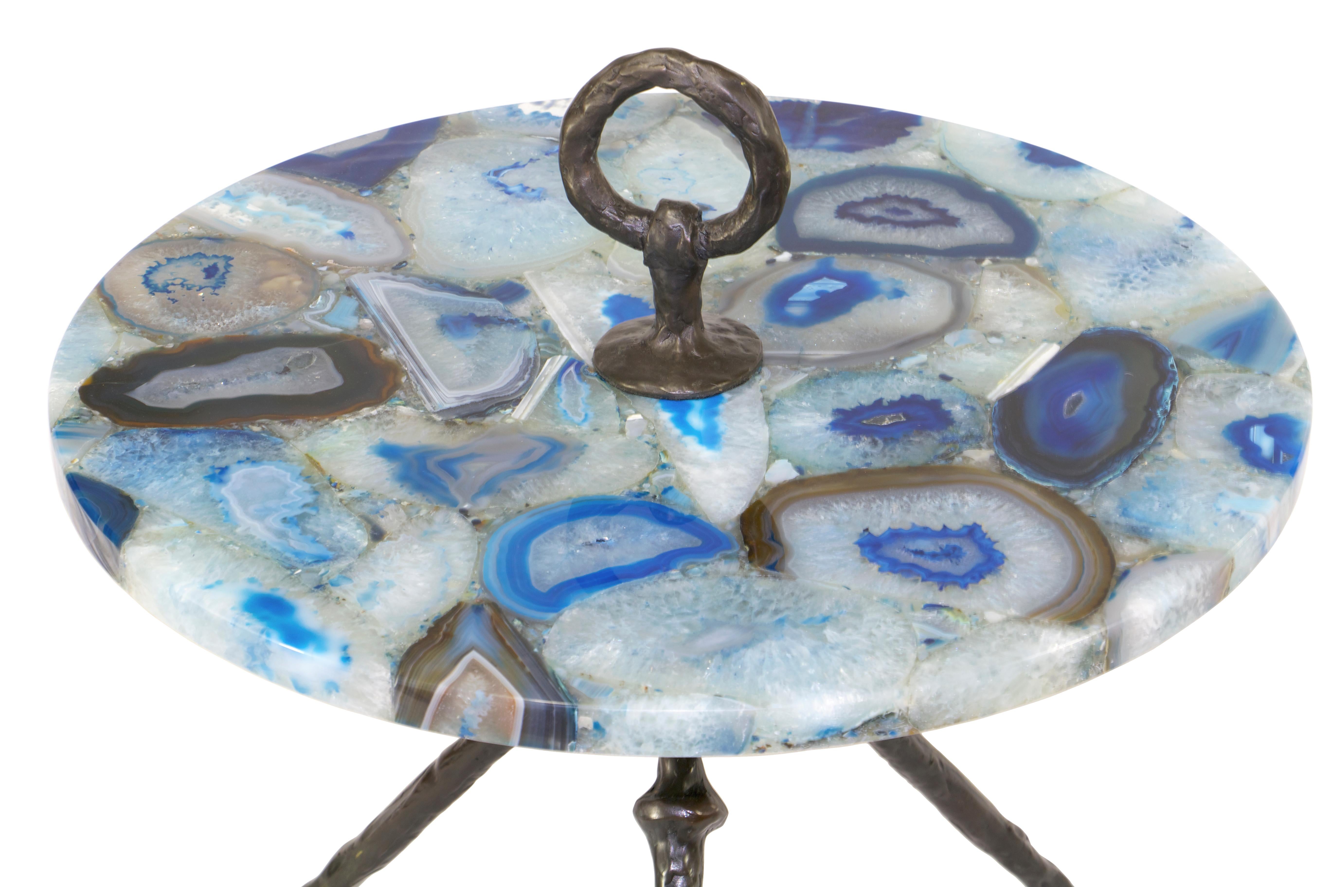 A hand-sculpted and forged bronze tripod cocktail table with a circular stone top, it is fastened with a solid bronze handle on top. Custom sizes, finishes and tops available.