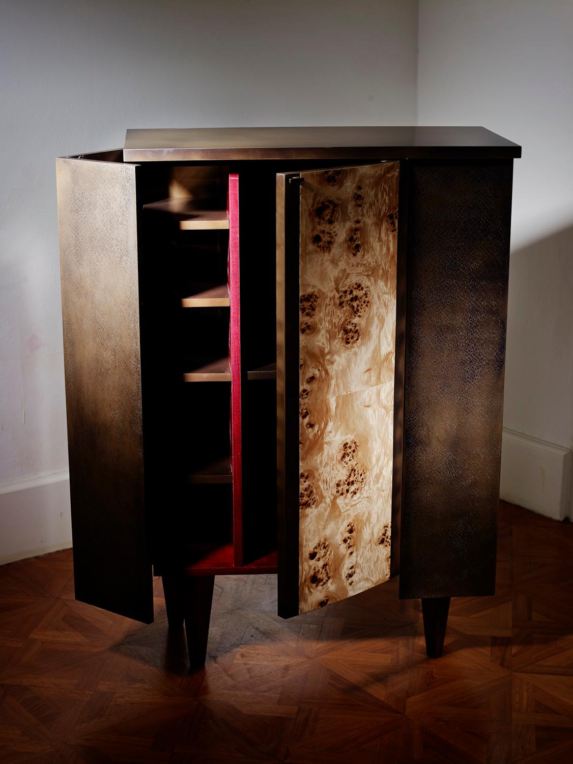 Burnished bronze over carved wood.
Finely chiselled door fronts covered with burnished bronze.
Central door in Poplar burl. Inside divided into shelves, in polished purpleheart wood.
Dimensions: H 120 x W 80 x D 36 cm. Edition of 8 (2