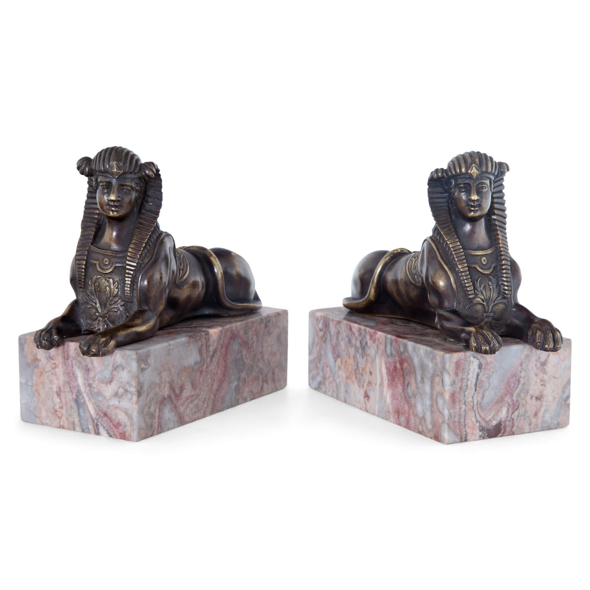 A true pair of bronze sphinxes of opposite design mounted on marble pedestals.
 