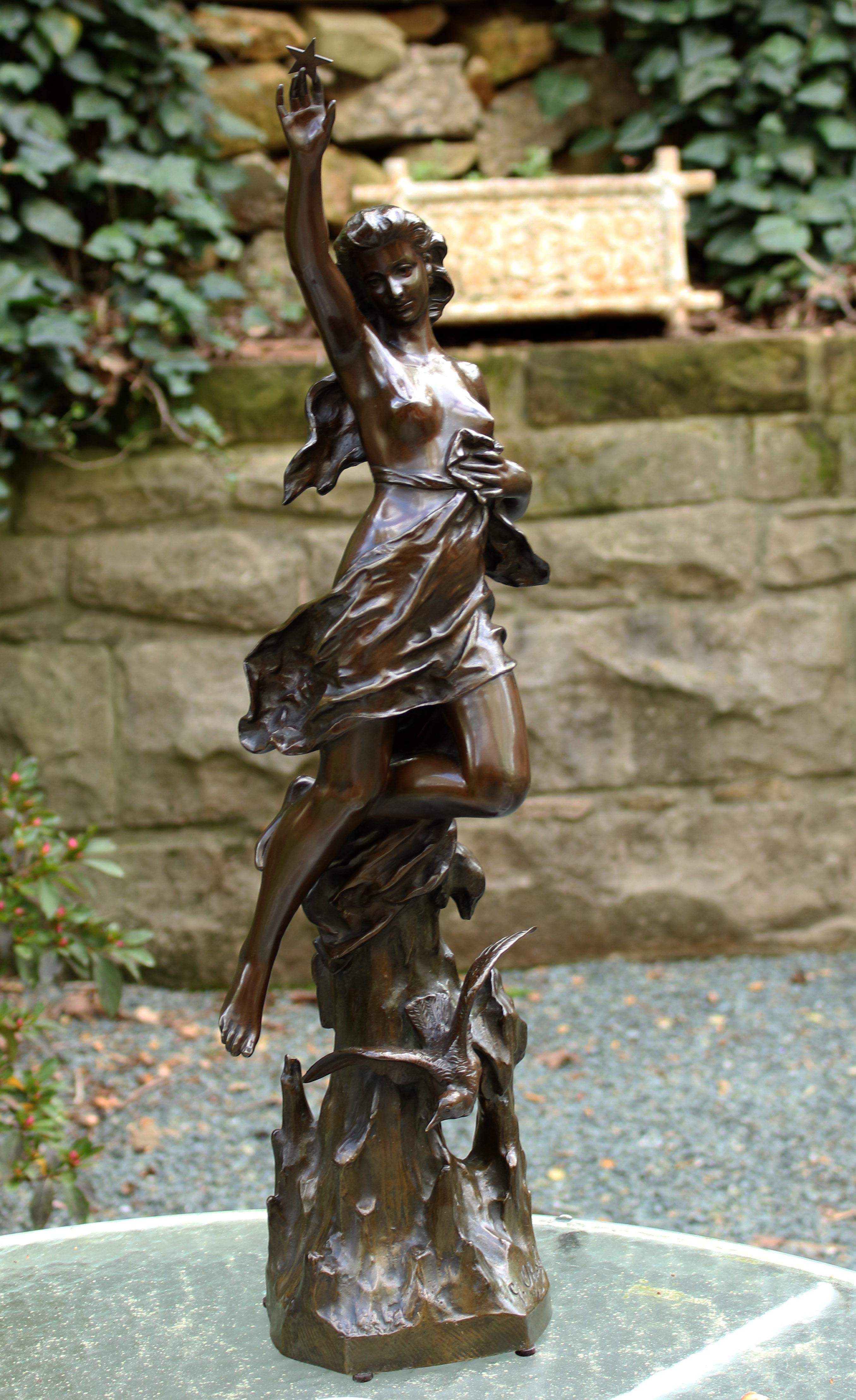 A bronze statue by Gustava Obiols Delgado (Spain, 1858-1910), signed G. Obiols. A woman holding a star as a bird swirls at the base. Soft brown patination. 26.75