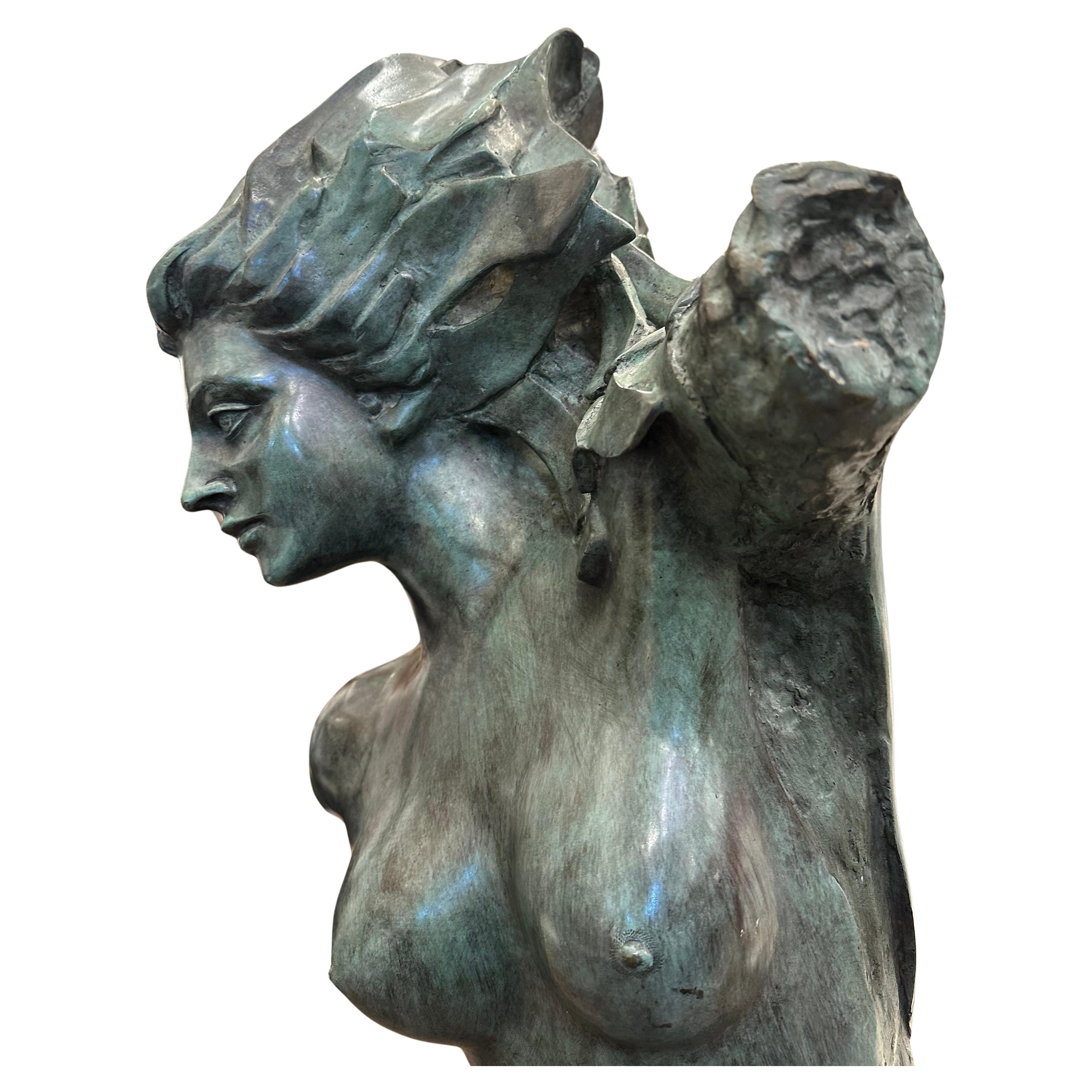 Bronzestatue einer weiblichen Figur auf schwarzem Marmorsockel.