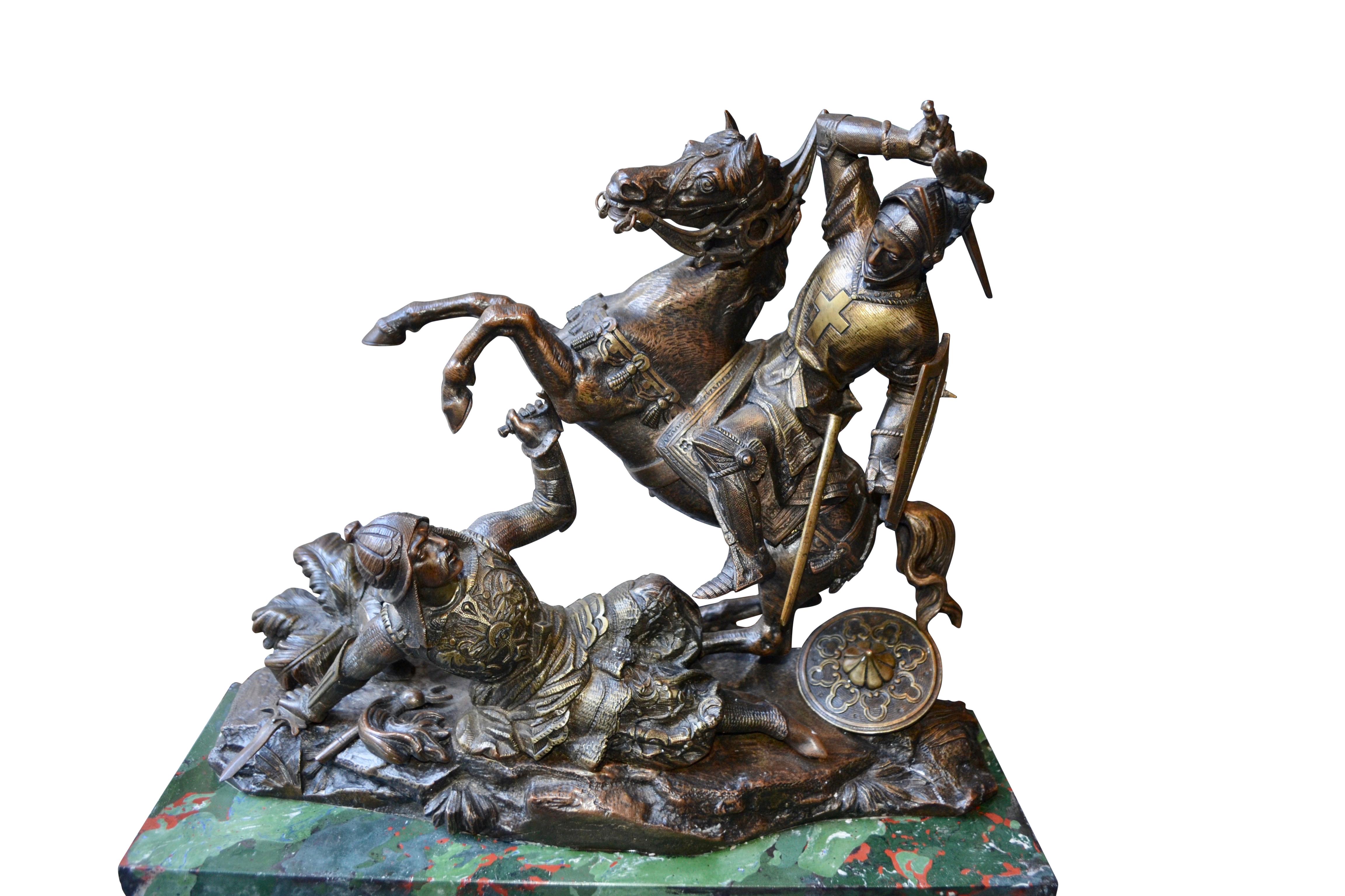 A dramatic patinated bronze statue depicting a mounted crusader on his rearing horse ready to strike a mortal blow to a fallen Saracen lying beneath him on a rocky landscape. In a desperate attempt to defend himself the Saracen is shown thrusting